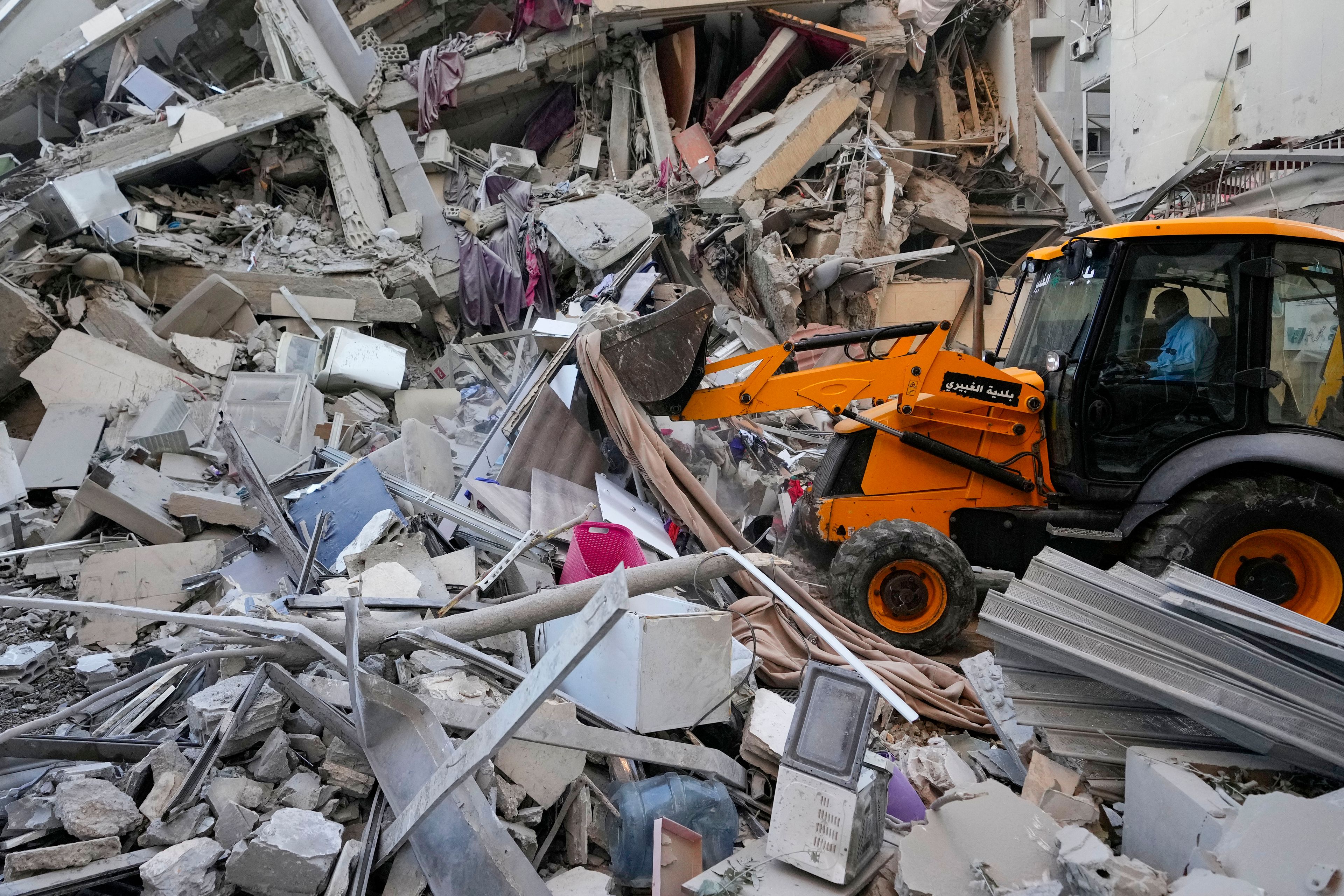 Rescue workers use a bulldozer to remove rubble of destroyed buildings at the site of an Israeli airstrike on Sunday night that hit several branches of the Hezbollah-run al-Qard al-Hassan in Beirut's southern suburb, Lebanon, Monday, Oct. 21, 2024. (AP Photo/Hassan Ammar)