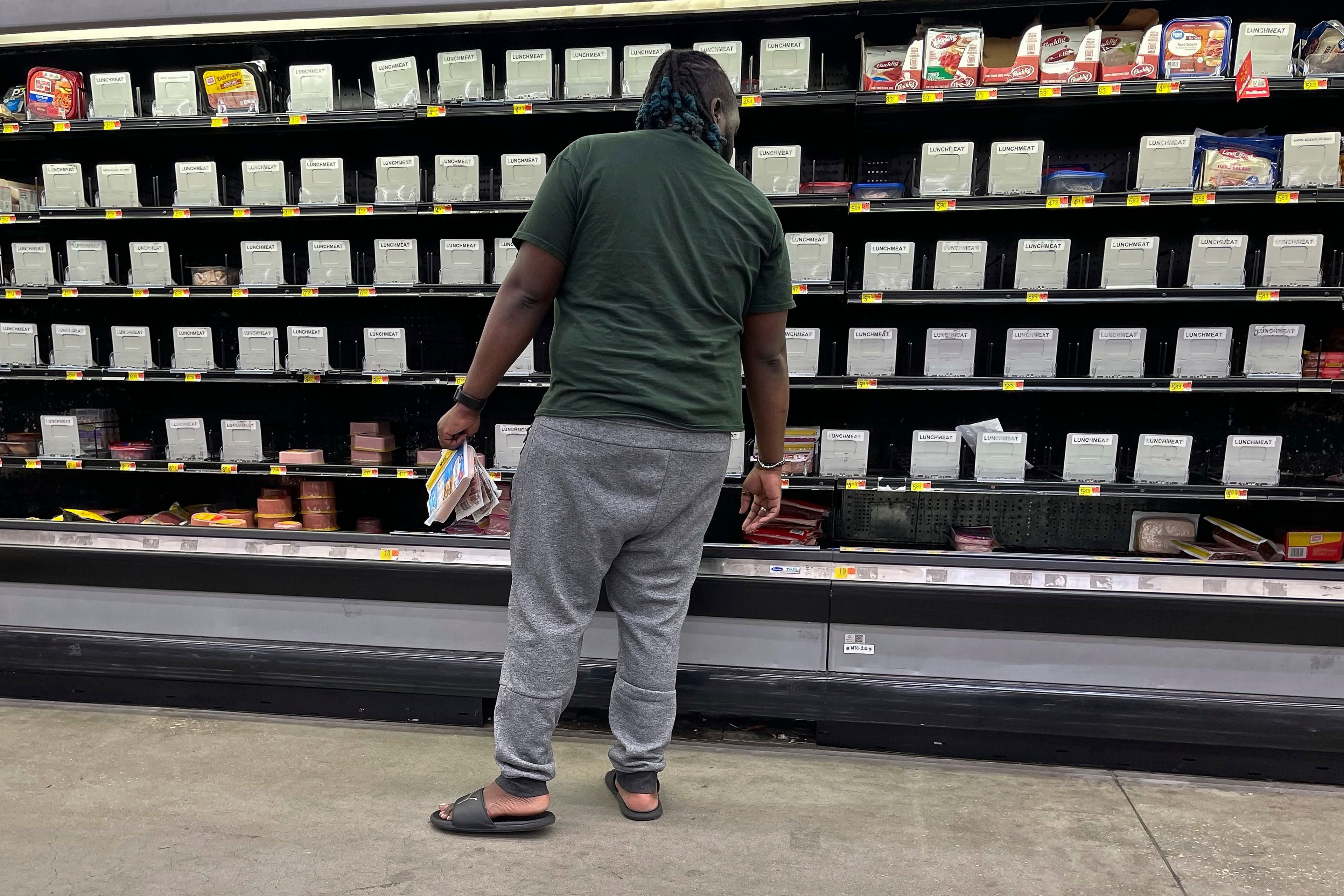 A shopper checks out nearly empty shelves in the lunch meat section of a Walmart, Wednesday, Sept. 25, 2024 in Tallahassee, Fla. Grocery stores and gas stations were seeing heavy traffic in advance of Hurricane Helene, expected to make landfall Thursday night in the Big Bend area. (AP Photo/Phil Sears)