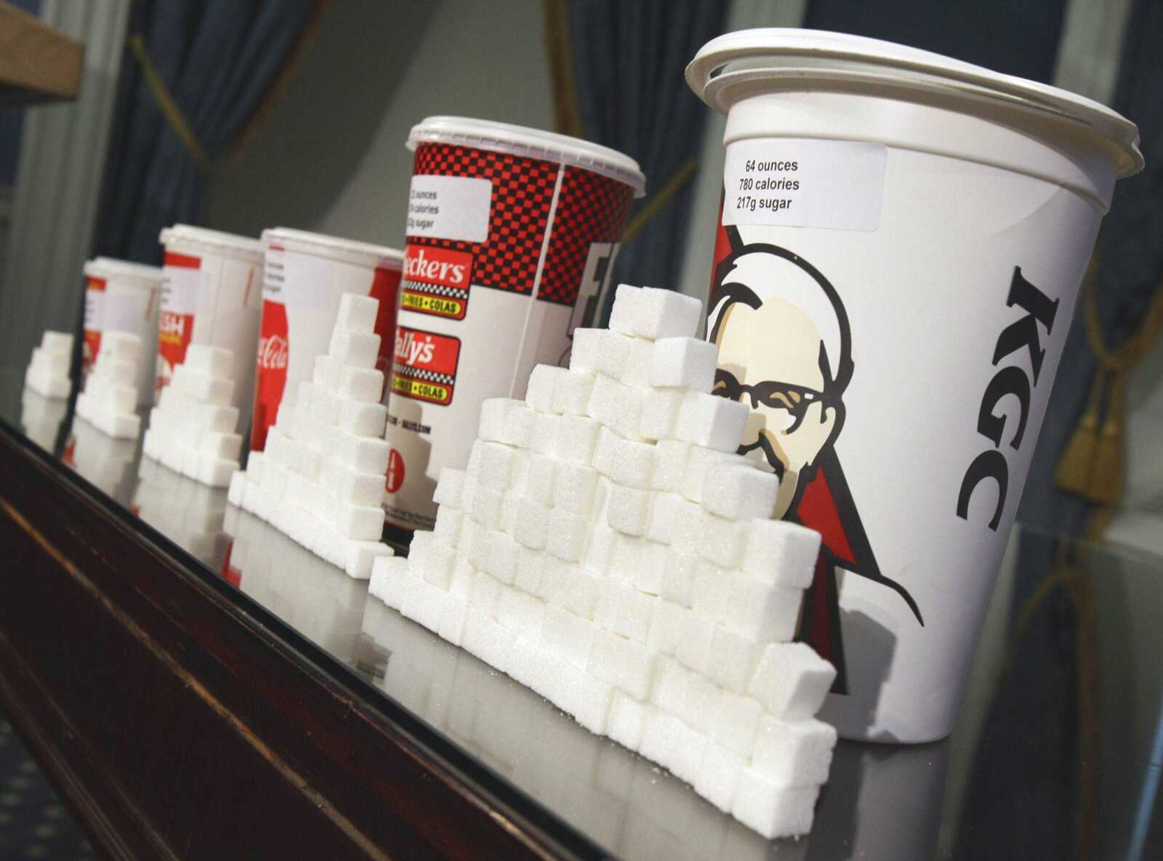 Various soft drink cups are next to stacks of sugar cubes at a news conference May 31 at New York's City Hall. Two major experiments found that children and teens gained less weight when they regularly drank calorie-free beverages instead of sugary ones. A third study gives the first clear evidence that consuming sugary drinks interacts with genes that affect weight. (Richard Drew ~ Associated Press)