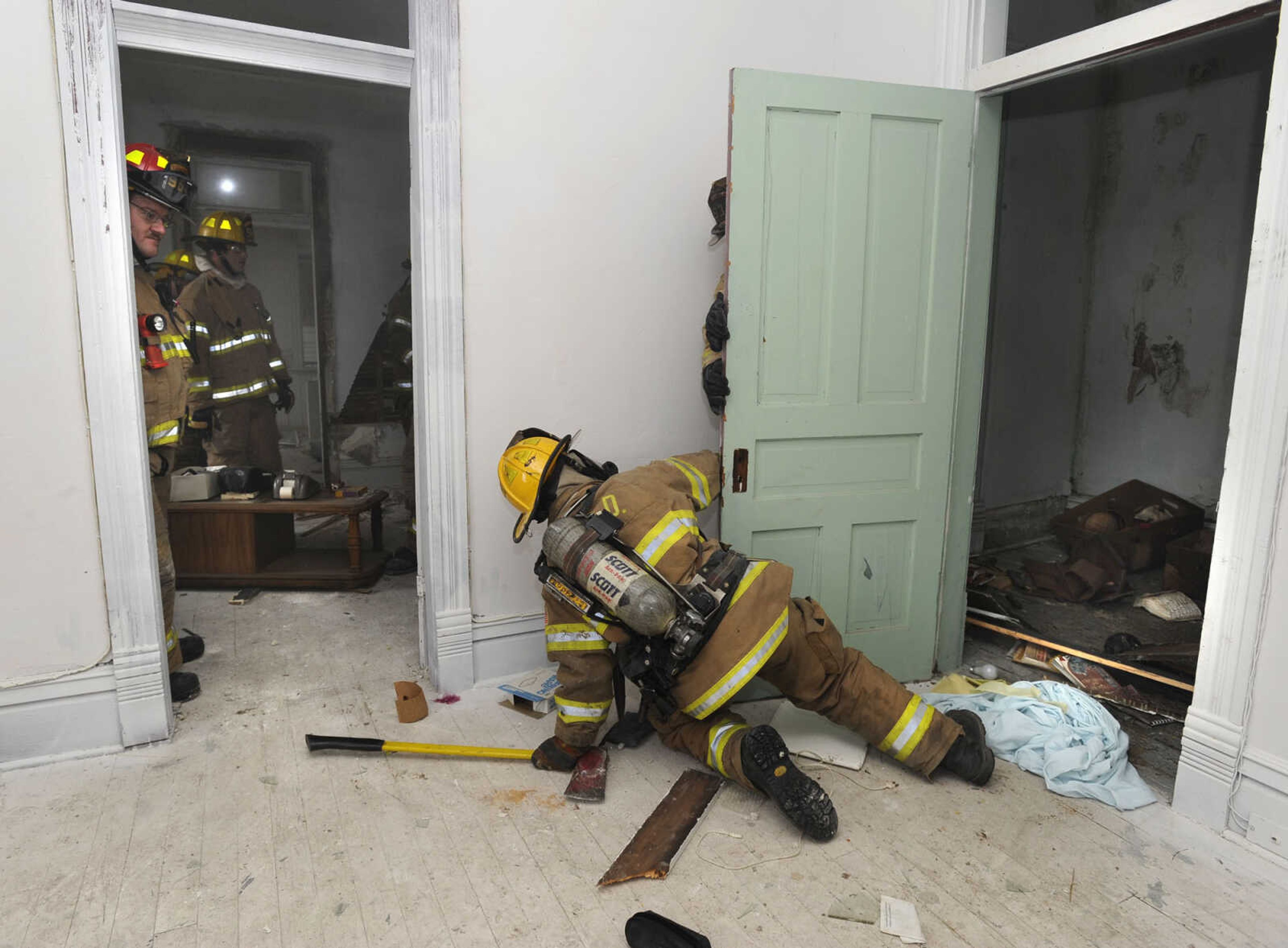 Firefighter Sam Jenne simulates searching a smoke-filled room after entering from the window.