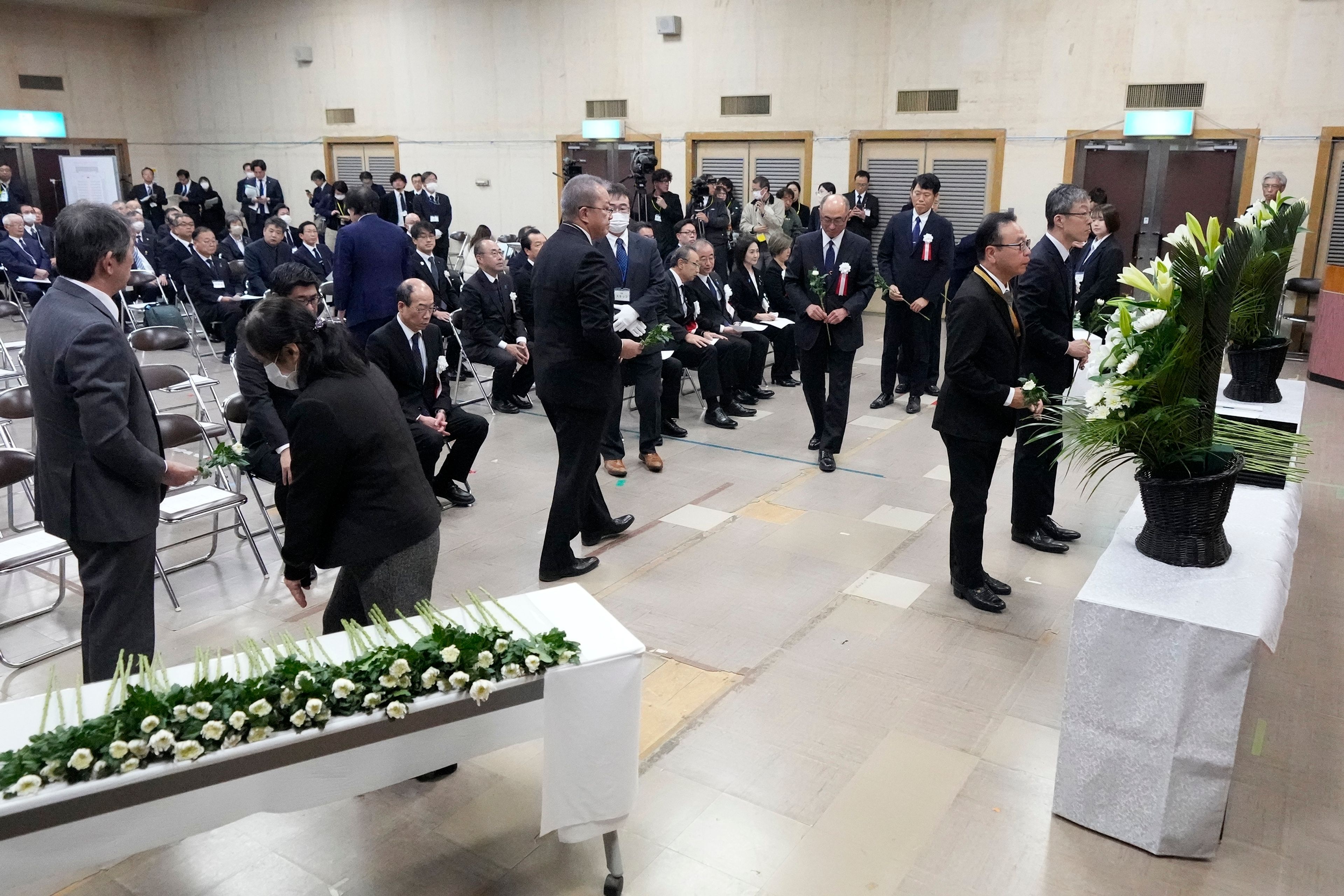 Guests offer a flower during a memorial ceremony for the Sado Island Gold Mine in Sado, Niigata prefecture, Japan, as several seats reserved for South Korean guests remained empty Sunday, Nov. 24, 2024. (AP Photo/Eugene Hoshiko)