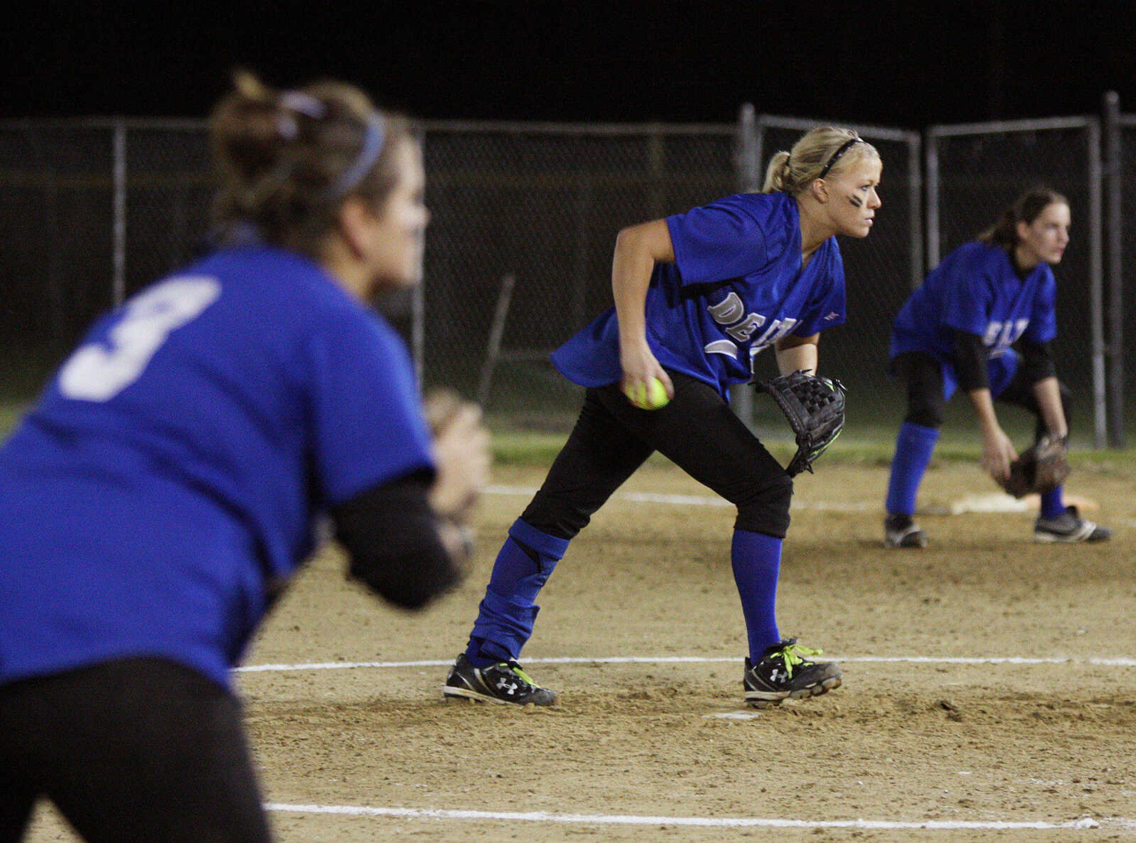 Delta pitcher, Kendra Burnett, begins to wind up a pitch while Courtney Burton, left, and Ashley Glaus, right, get in position for a hit.