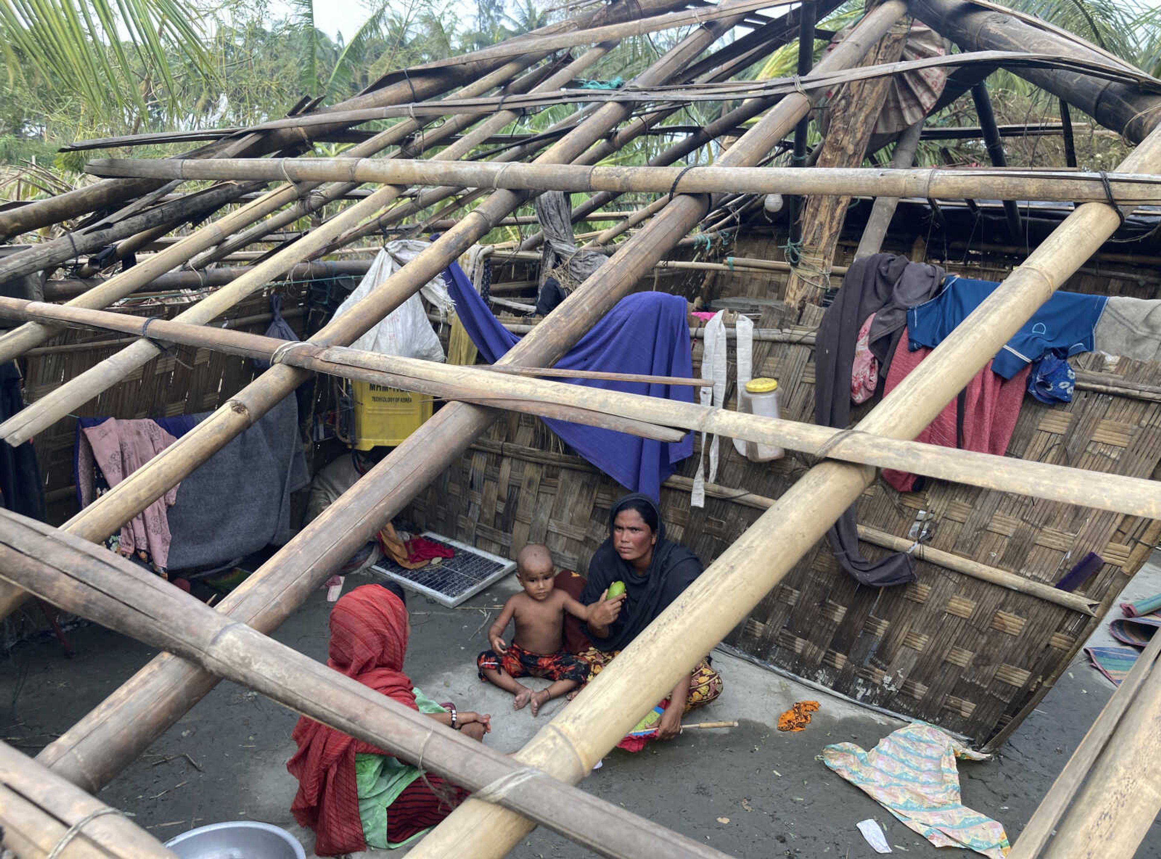 A family rests Monday inside their home damaged by Cyclone Mocha at Saint Martin island in Cox's Bazar, Bangladesh.