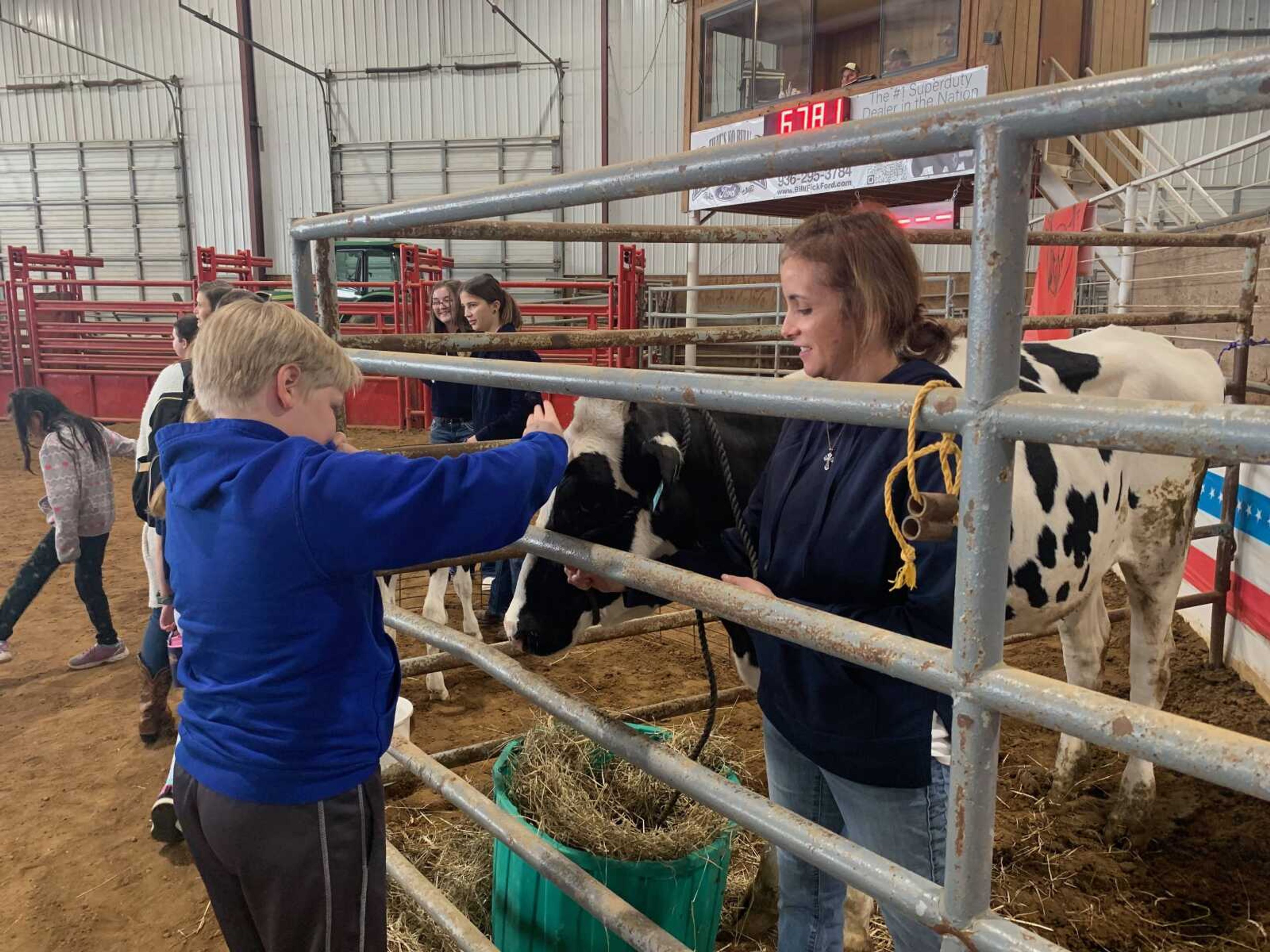 A South Elementary student pets Apple the dairy cow, while Melinda Morrison holds the cow still. Dairy cows are milked twice daily to empty their udders.