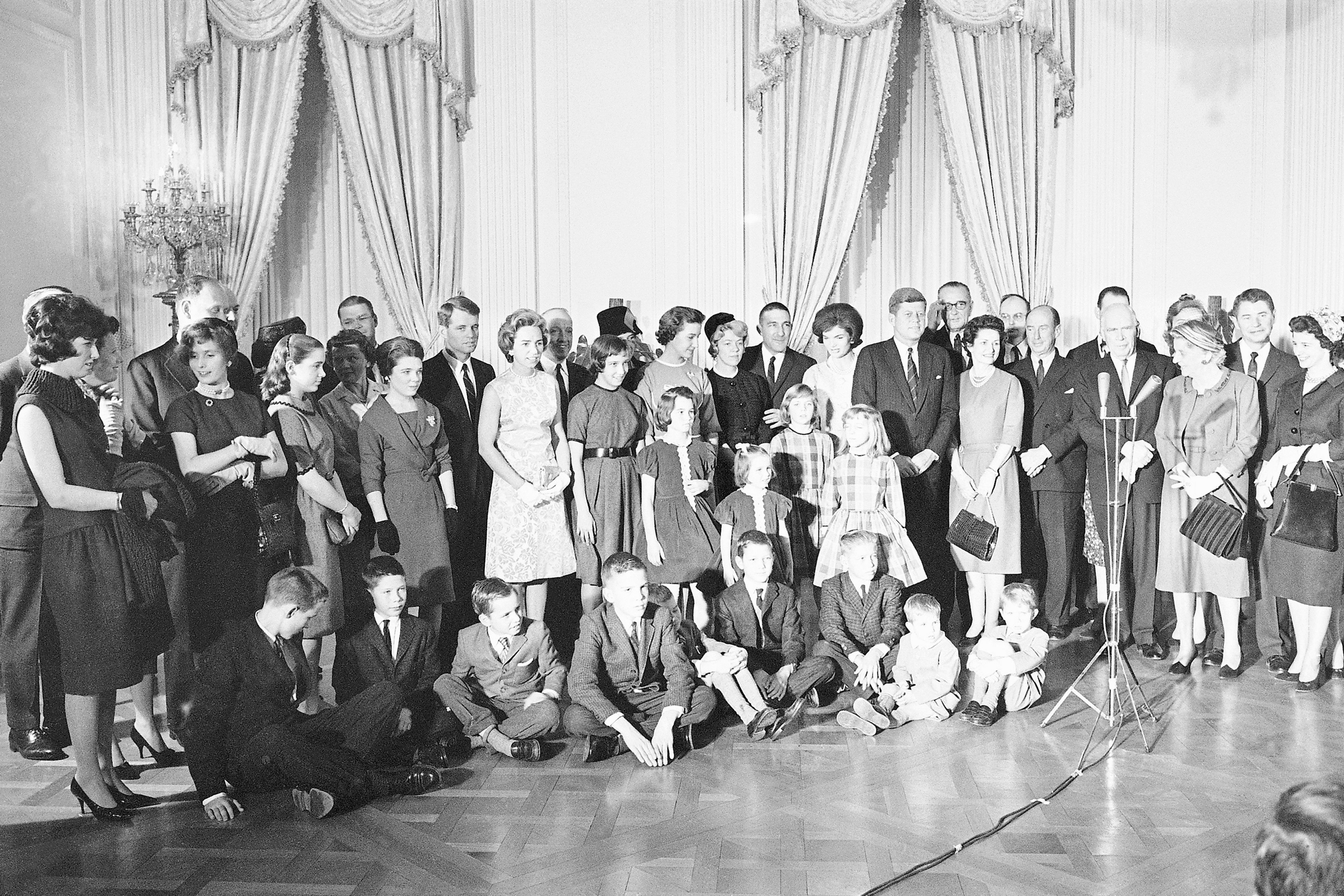 FILE - Children of three cabinet offices fill the foreground as President John Kennedy and Mrs. Jacqueline Kennedy pose with guests at a White House reception in the East Room, Jan 21, 1961. The children are those of Attorney General Robert Kennedy, Postmaster General Edward Day, and Interior Secretary Stewart Udall. Seated on floor, from left: Joe Kennedy, 8, Jimmy Day, 12, Bobby Kennedy, 6, Scott Udall, II, Tommy Udall, 12, Michael Kennedy, 2, and David Kennedy, 5. Four girls at center, from left; Kathleen Kennedy, 9, Courtney Kennedy, 4, Lynn Udall, 10, and Lori Udall, 8. Back row: Robert Kennedy, his wife Ethel, Edward Day, Molly Day, 14, and Mrs. Day. Hidden: Geraldine Day, 17; Mrs. Irma Udall, the First Lady, the president, Vice President Johnson, Mrs. Lady Bird Johnson, Frederick Dutton of White House staff and Adlai Stevenson, ambassador to the United Nations. (AP Photo/William Allen, File)