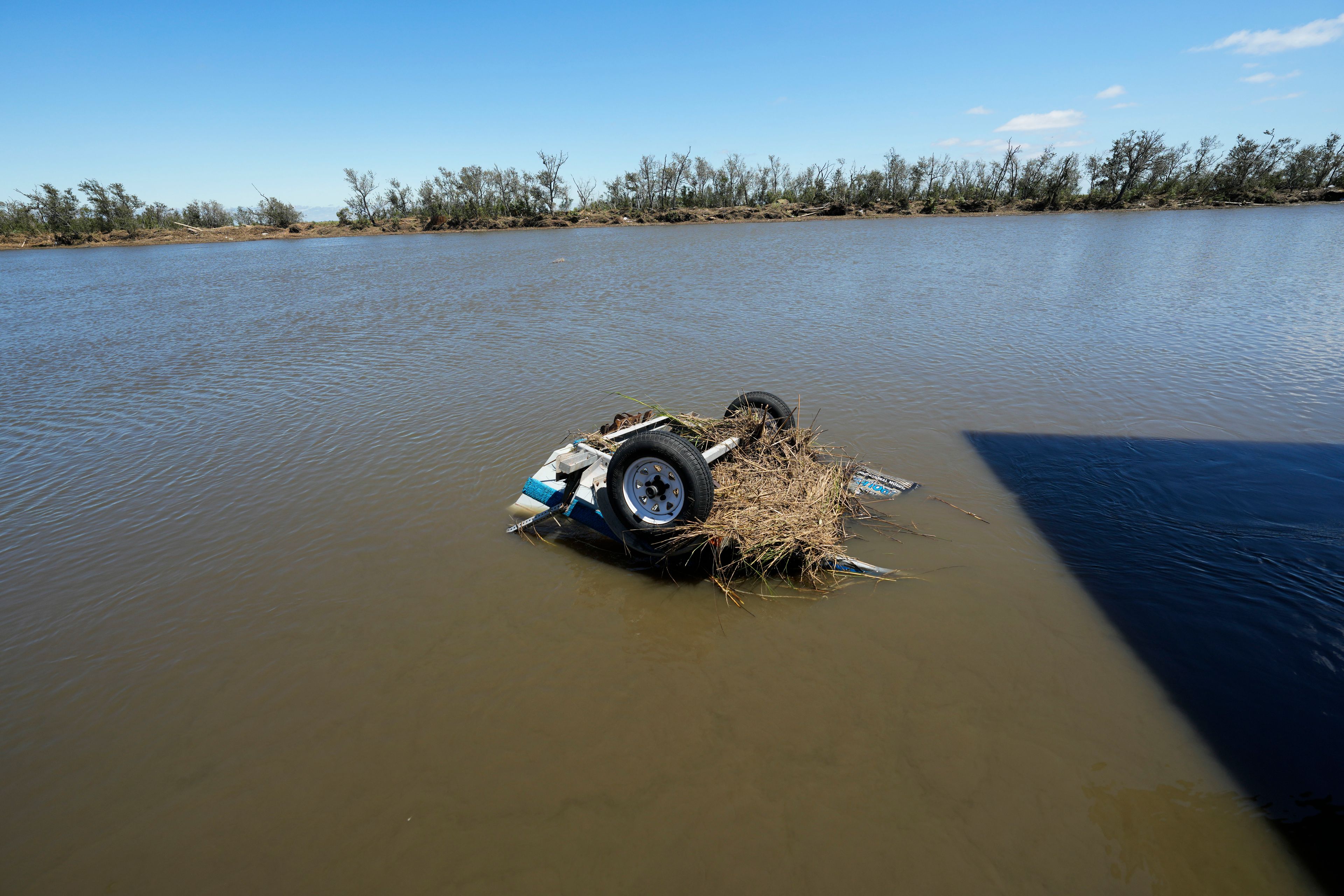 An overturned boat sits in the bayou behind the home of resident Bill Andrews in the aftermath of Hurricane Francine in Cocodrie, La., Thursday, Sept. 12, 2024. (AP Photo/Gerald Herbert)