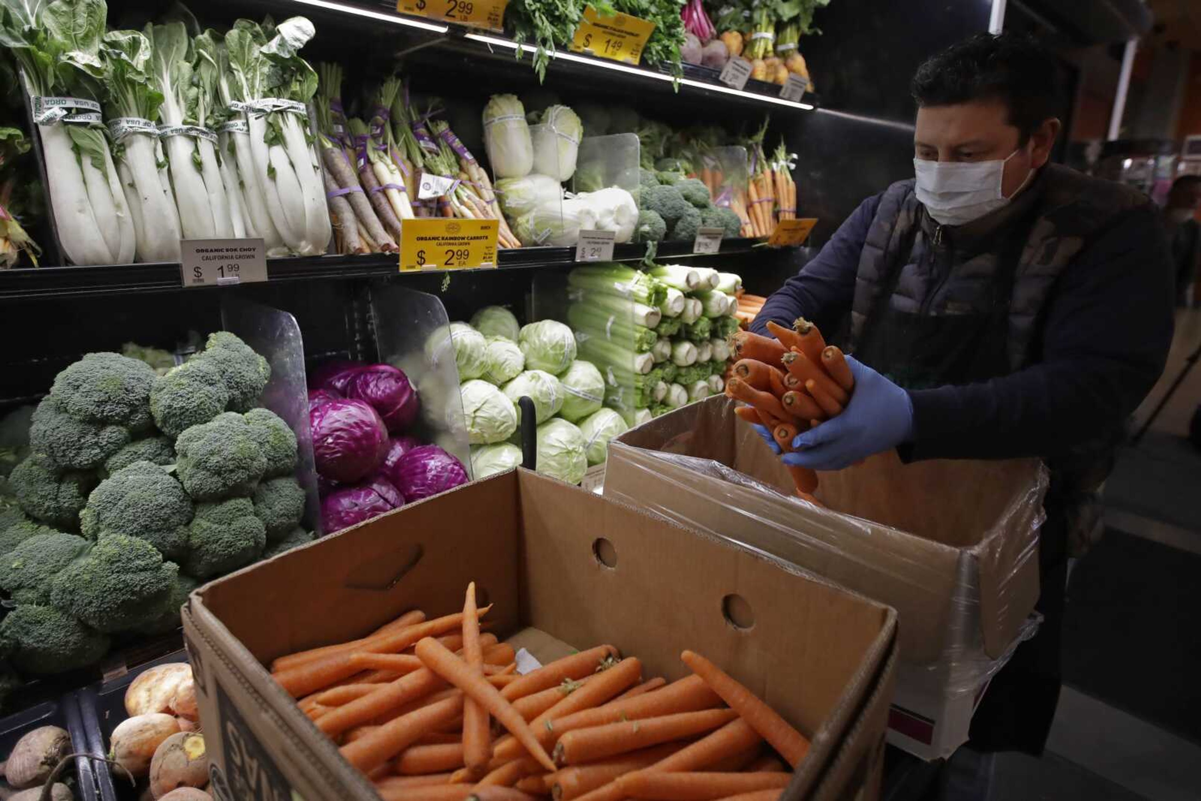 A worker stocks produce before the opening of a market March 27, 2020, in San Francisco.