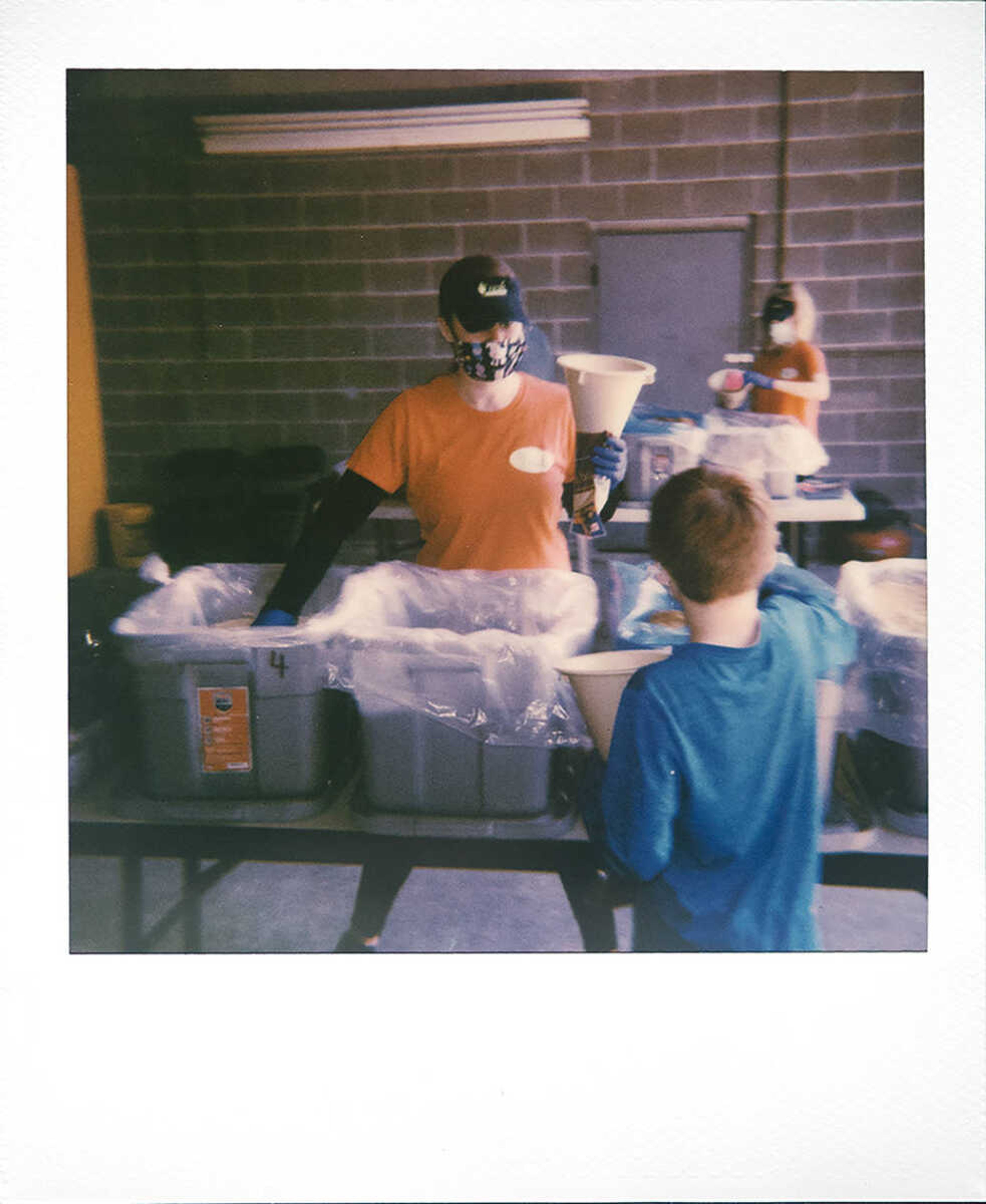 Fresh Healthy Cafe employee Molly Clark of Jackson (foreground in orange) and Camdyn Powell, 7, pack meals through Kids Against Hunger near cafe employee Jillian Olson of Cape Girardeau (in background) on Friday, April 24, 2020, in Cape Girardeau. Rick Hetzel, Southeast Missouri satellite director for Kids Against Hunger, said employees from Fresh Healthy Cafe in Cape Girardeau are regularly packing meals. "We anticipated there would be people that probably because of the layoffs and the economy would need food. And so about a month ago we ordered in enough for 100,000 meals with our Kids Against Hunger satellite," Hetzel said.