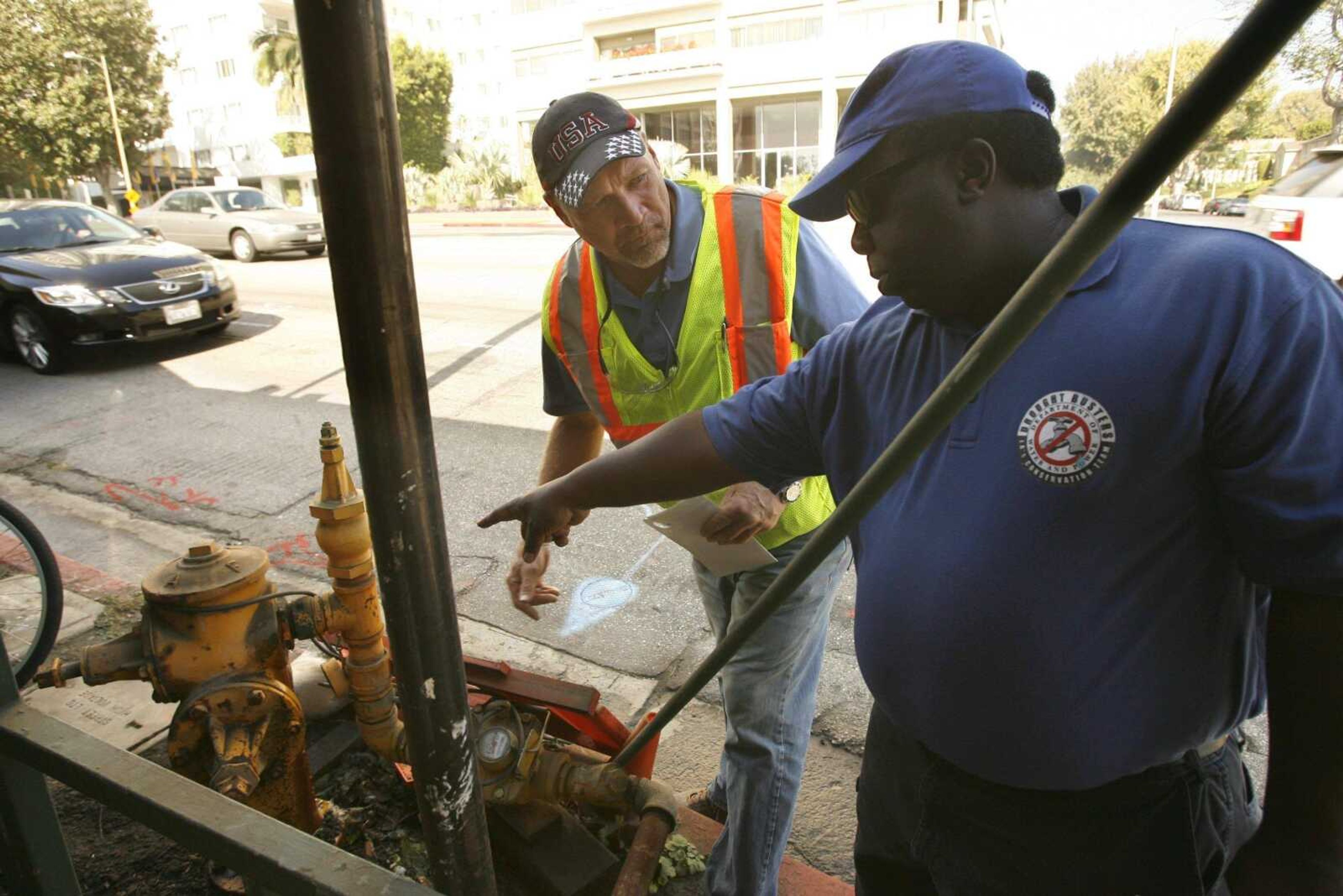 Damian Dovarganes ~ Associated Press<br>David Chase, a general superintendent, checks a leaky city connection Oct. 21 during an inspection by a member of the Los Angeles Department of Water & Power, right, in Los Angeles.