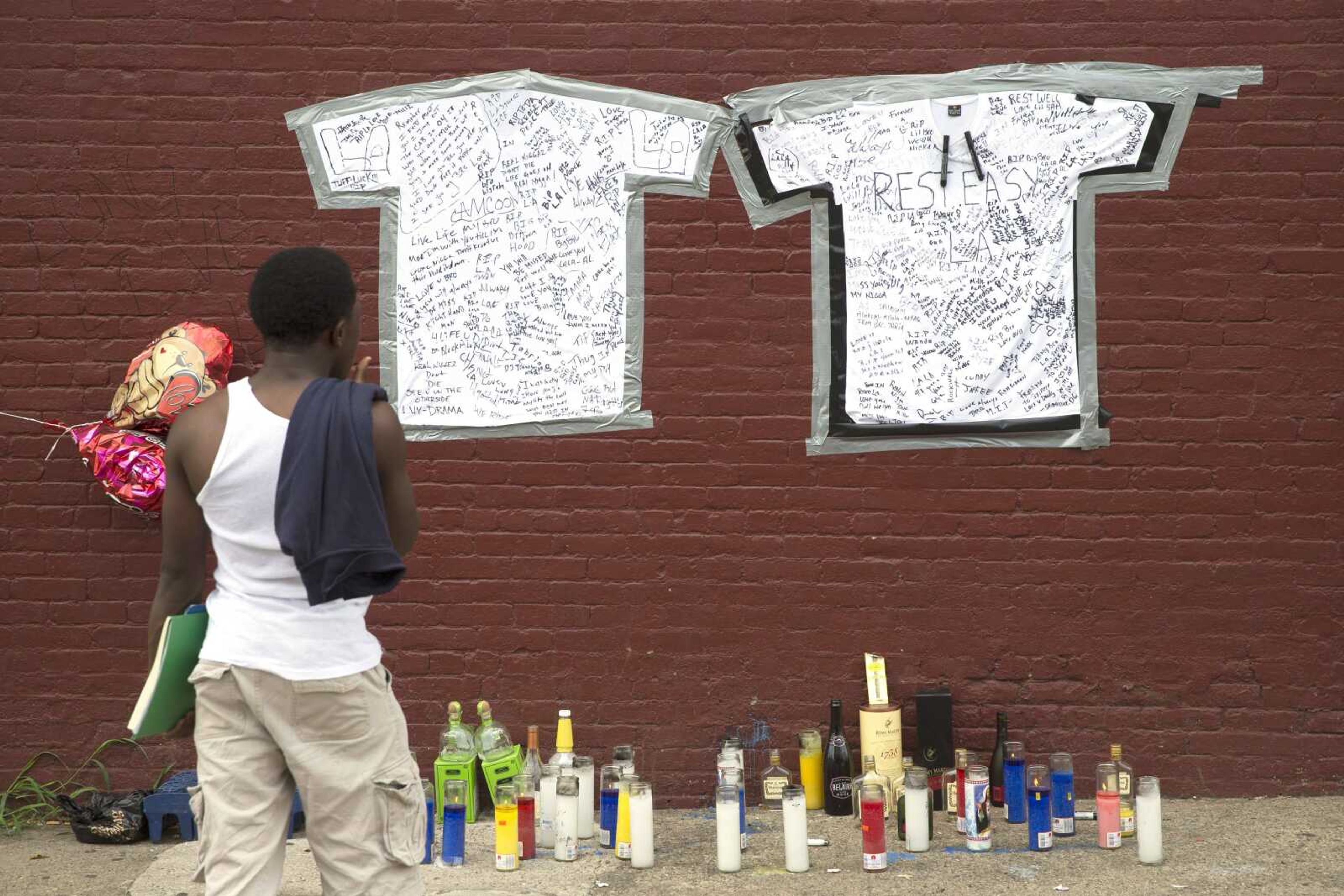 A pedestrian stands Monday at a memorial to Lawrence Campbell, who allegedly shot and killed 23-year-old Jersey City police officer Melvin Santiago, in Jersey City, New Jersey. Campbell also was killed at the scene after police officers returned fire. (John Minchillo ~ Associated Press)