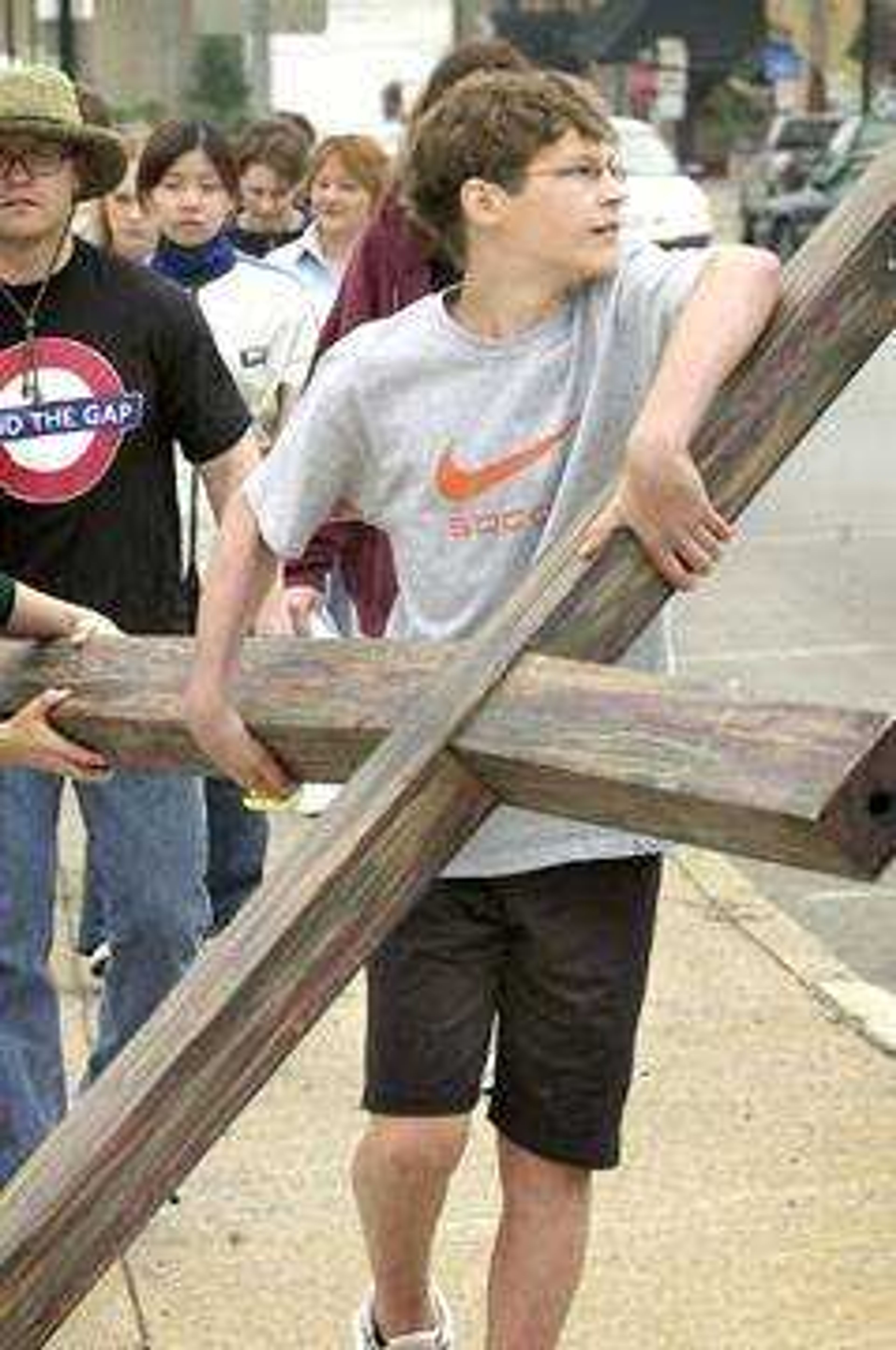 Joda Holloway carried a large wooden cross up Broadway during the Way of the Cross procession, which marked Good Friday.