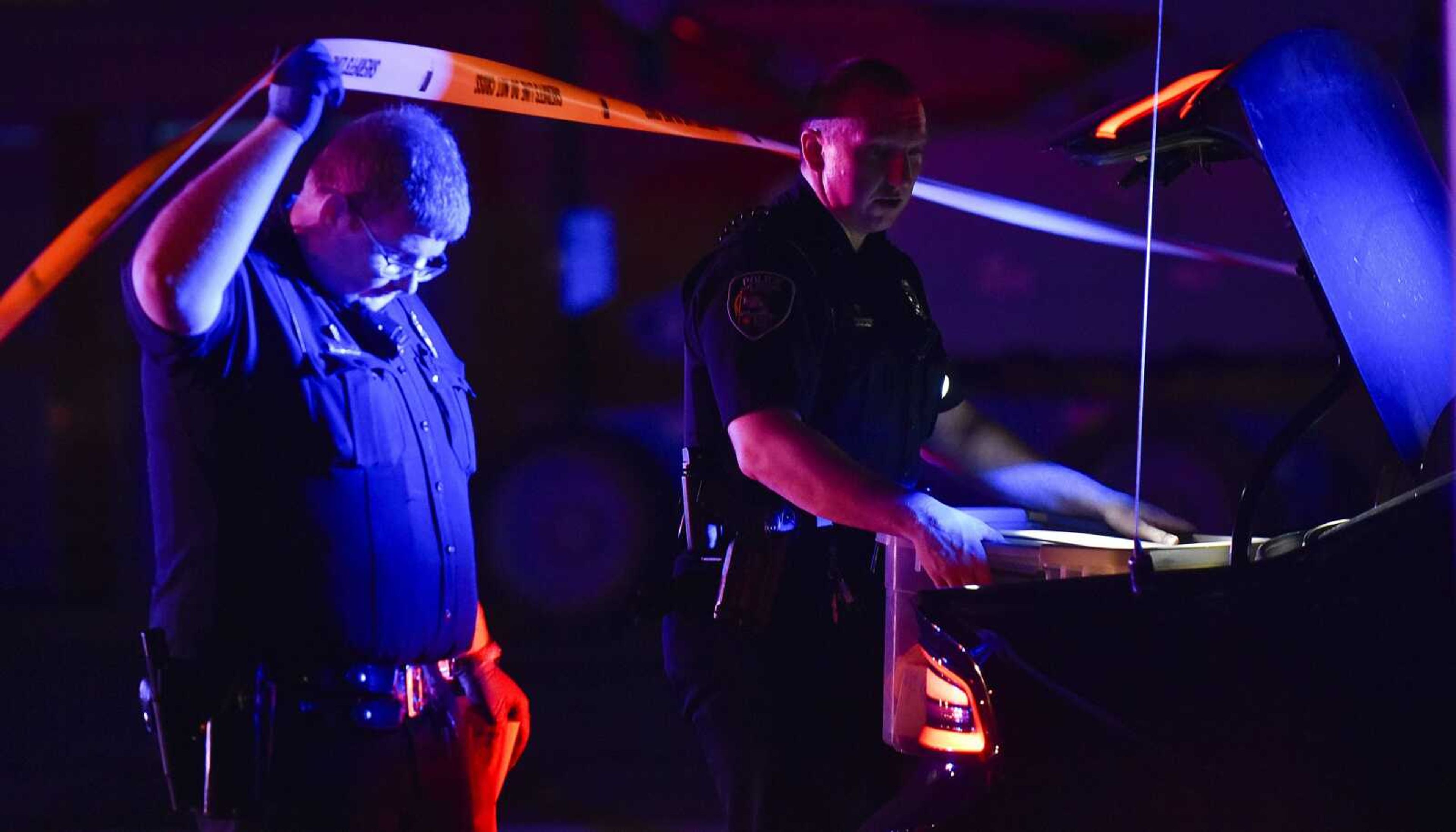 Cape Girardeau police officers Anthony Vezeau, left, and David Weidenbenner cross under caution tape to investigate the scene of a shooting, which sent one victim to an area hospital with non-life threatening injuries early May 3, 2018, in a parking lot near the intersection of Independence and South Main streets in Cape Girardeau.