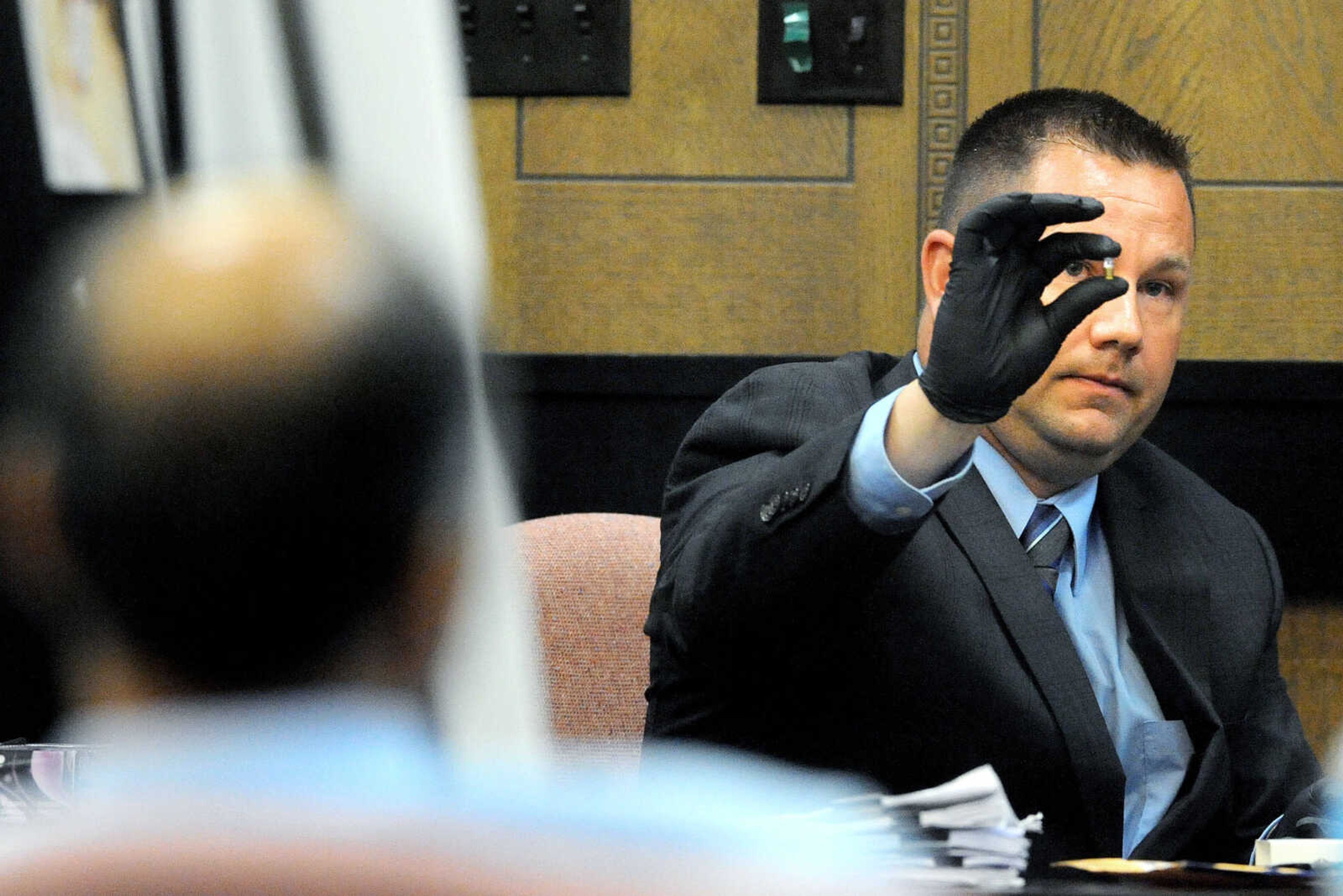 LAURA SIMON ~ lsimon@semissourian.com

George Joseph sits in the foreground as Det. Jeff Bonham with the Cape Girardeau Police Department holds up an spent shell casing from a .22 caliber handgun during his testimony, Monday, July 20, 2015, at the Cape Girardeau County Courthouse in Jackson, Missouri. The casing was found in Mary Joseph's bedroom during the police department's 2013 double-murder investigation. Joseph is accused in the 2013 shooting deaths of his wife, Mary Joseph, and son, Matthew Joseph, at their home on West Cape Rock Drive.