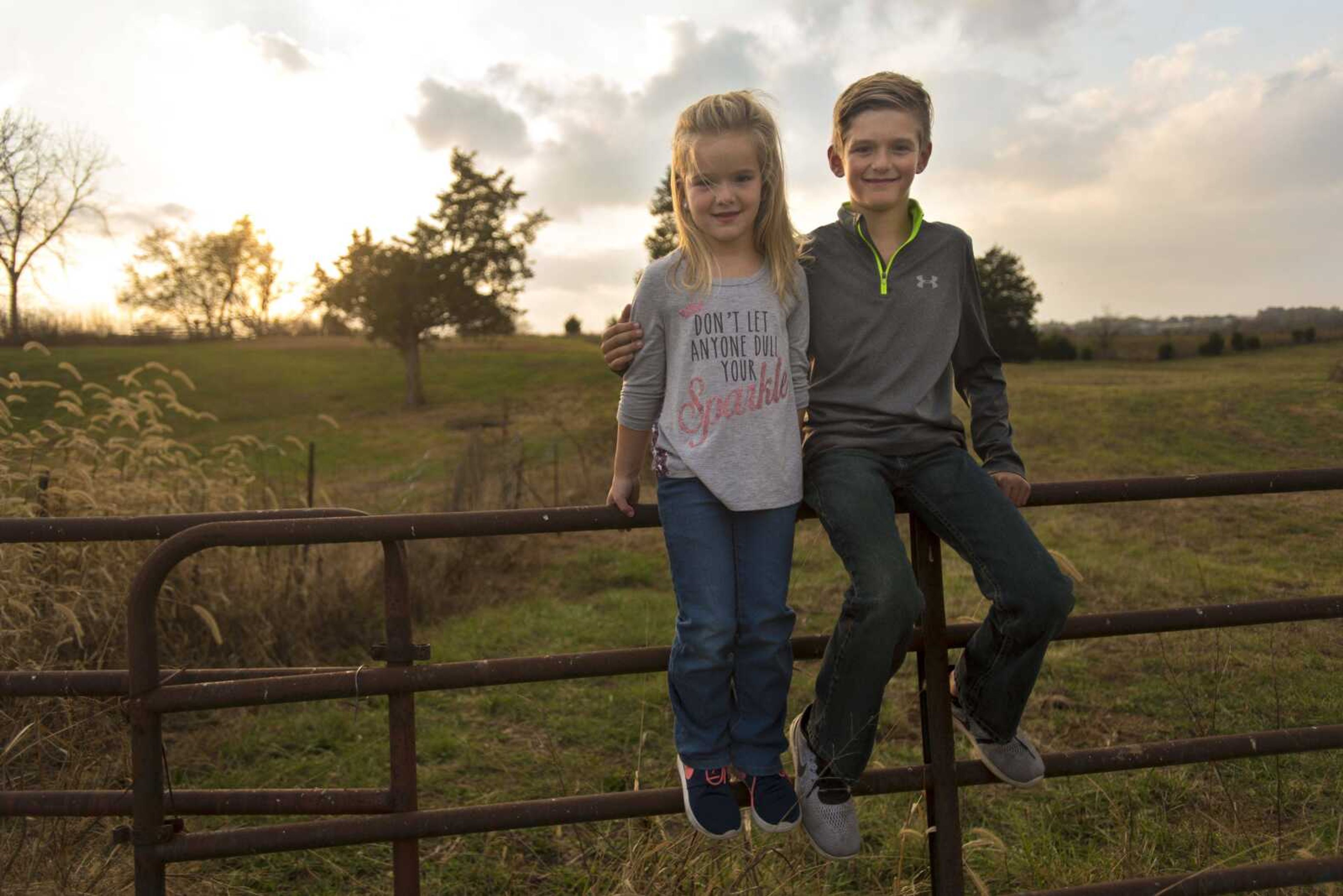 Raelyn Moore, 5, left, and her brother, Connor, 10, pose for a photo on their fence Nov. 2 in Perryville, Missouri.