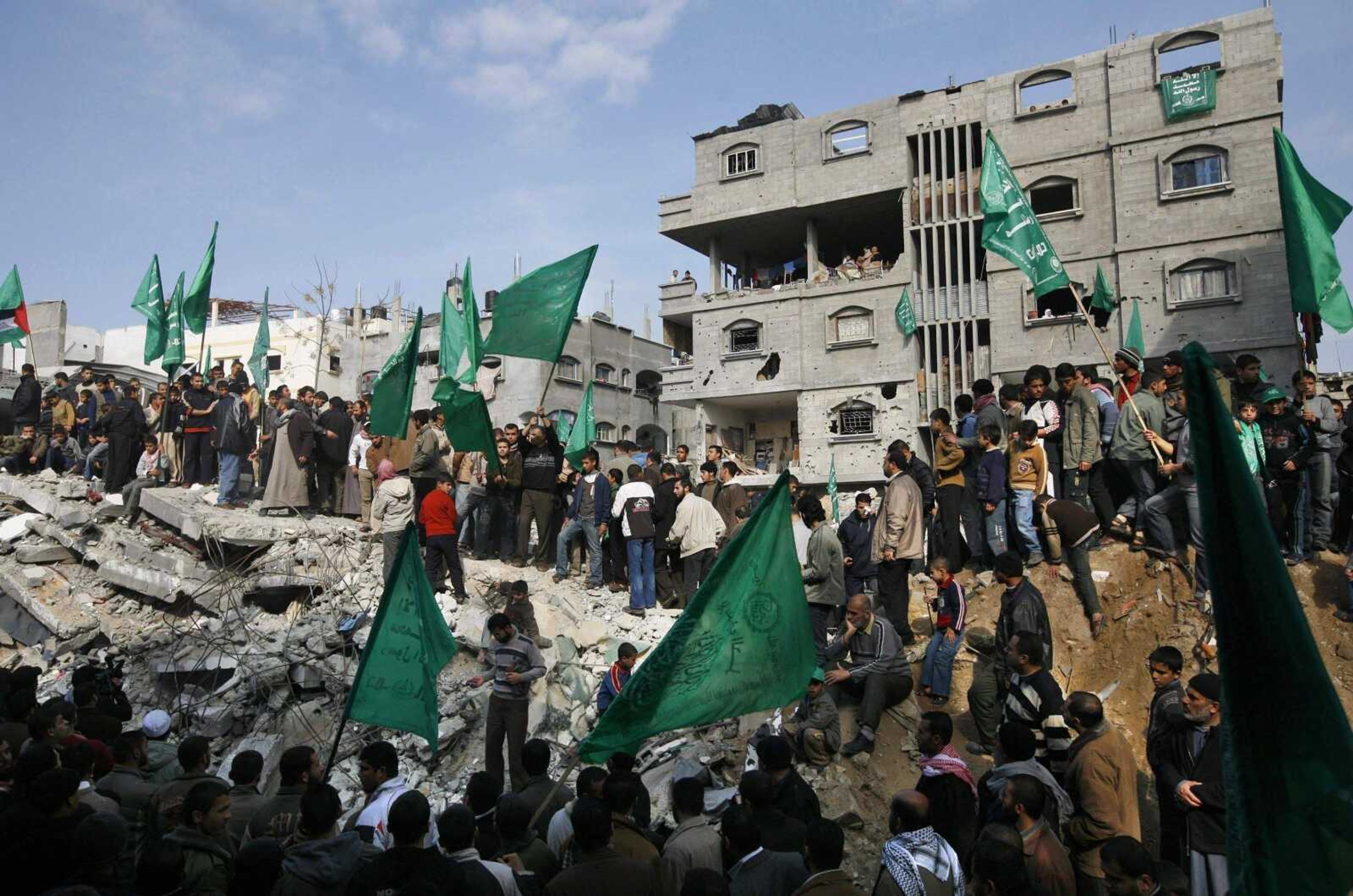 ANJA NIEDRINGHAUS ~ Associated Press<br>Palestinian men wave Hamas flags next to destroyed buildings during a march Tuesday through Jebaliya, northern Gaza Strip. Hamas leaders vowed to restore order to the territory Monday after Israel pummeled the militant group in a three-week war.