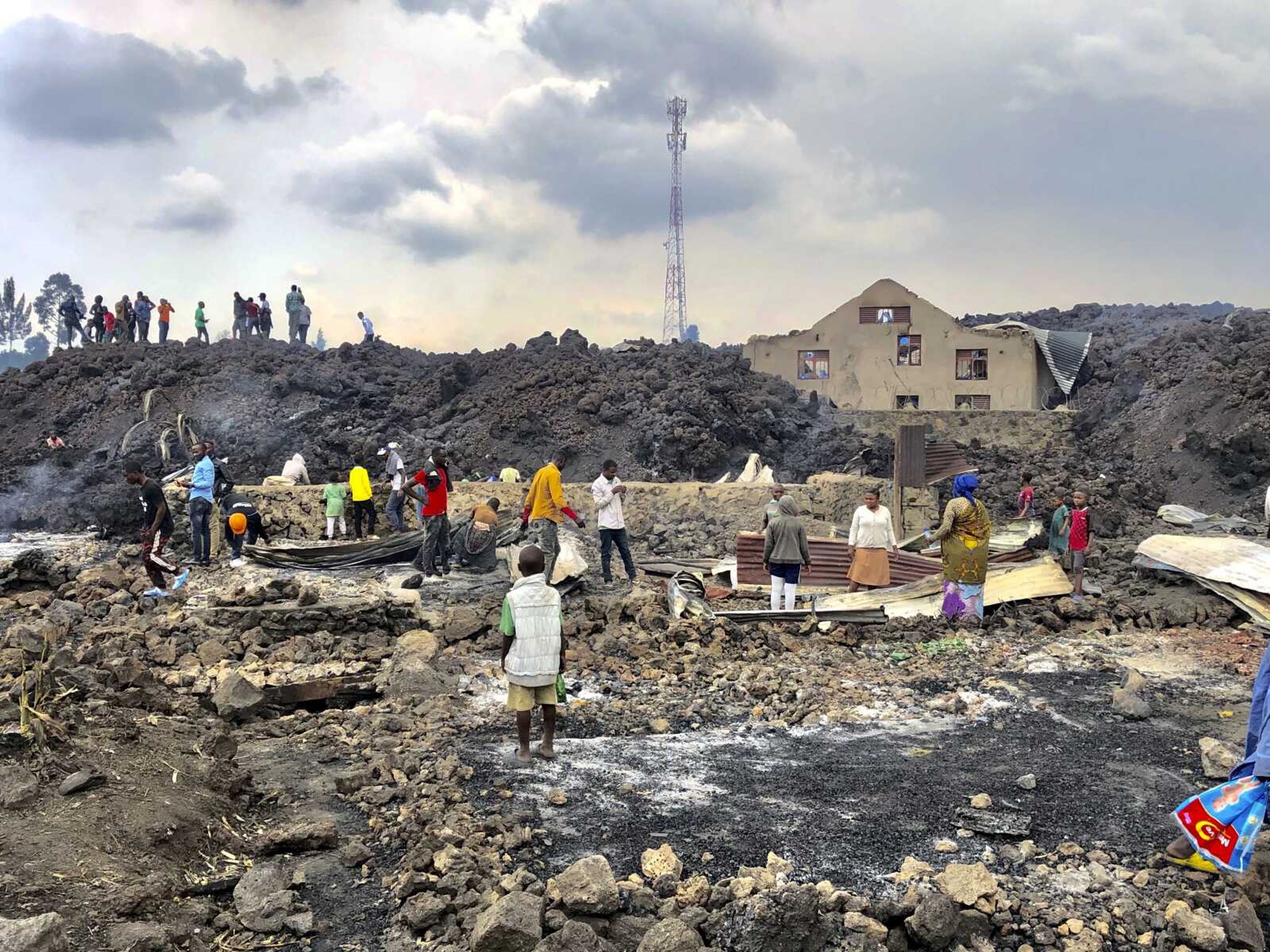 People gather on a stream of cold lava rock Sunday following the overnight eruption of Mount Nyiragongo in Goma, Congo. The volcano unleashed lava that destroyed homes on the outskirts of Goma but the city of nearly 2 million people was mostly spared after the nighttime eruption. Residents of the Buhene area said many homes had caught fire as lava oozed into their neighborhood.