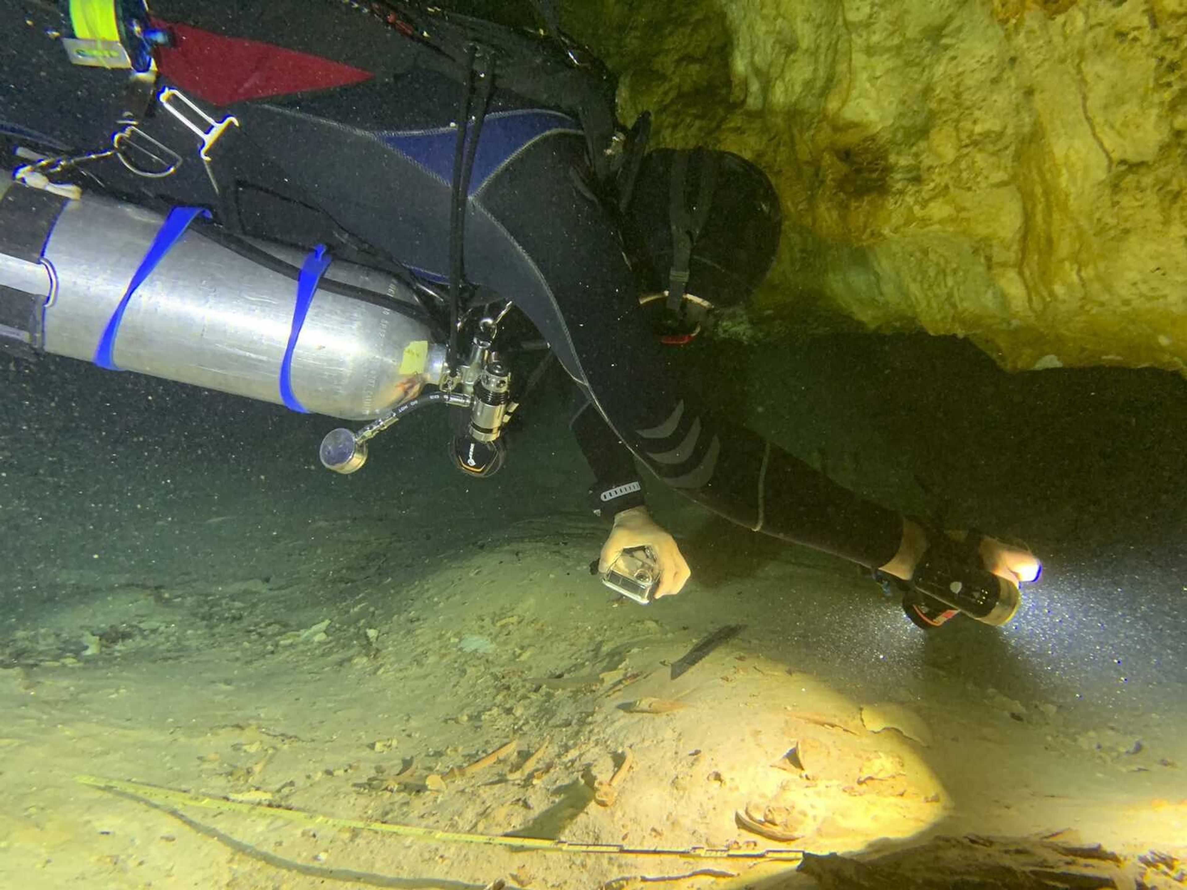 Aquatic archaeologist Octavio del Rio films a pre-historic human skeleton partly covered by sediment in an underwater cave Saturday in Tulum, Mexico.