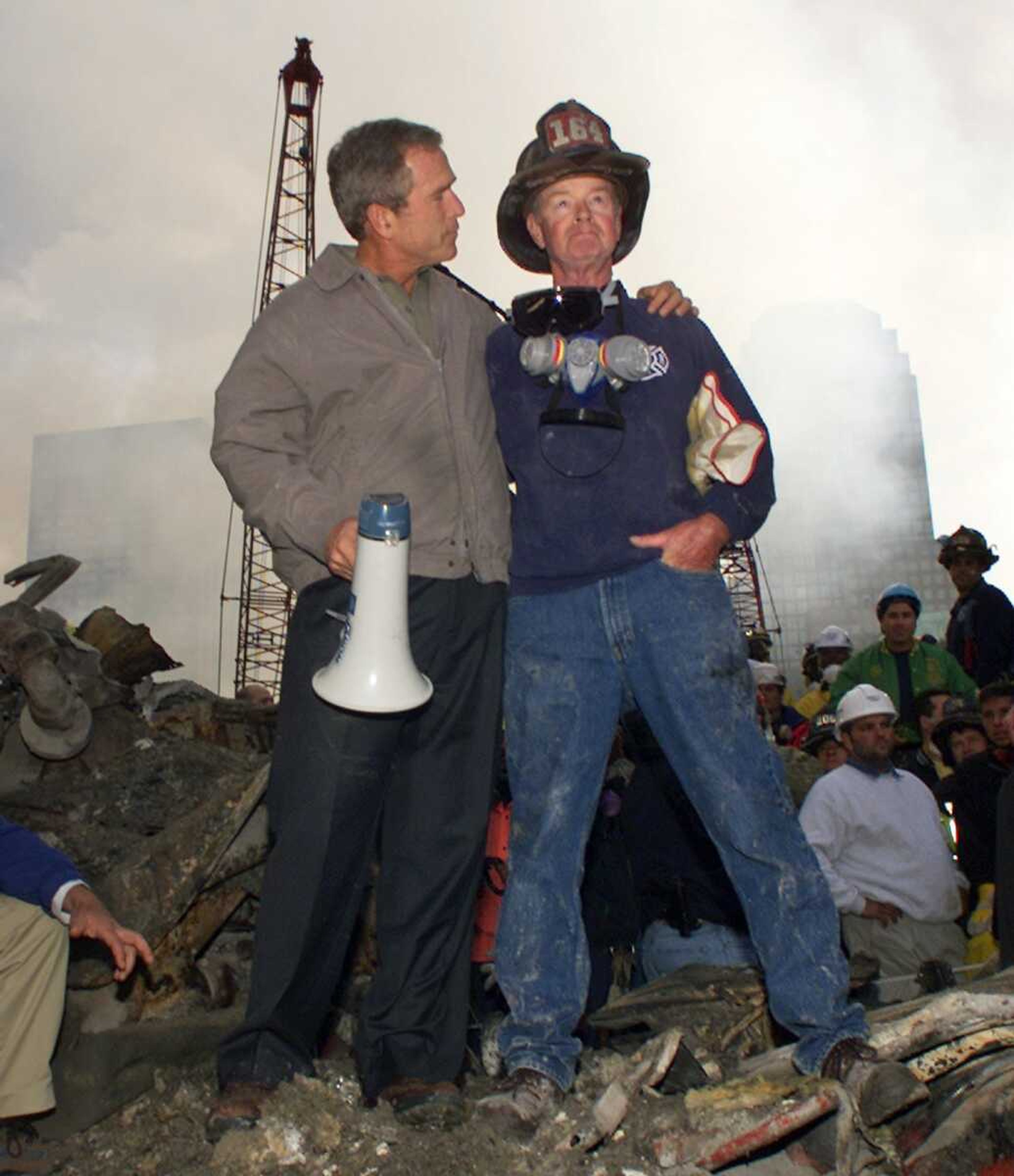 In this Sept. 14, 2001 file photo, as rescue efforts continue in the rubble of the World Trade Center, President George W. Bush puts his arms around firefighter Bob Beckwith while standing in front of the World Trade Center in New York. (AP Photo/Doug Mills, File)