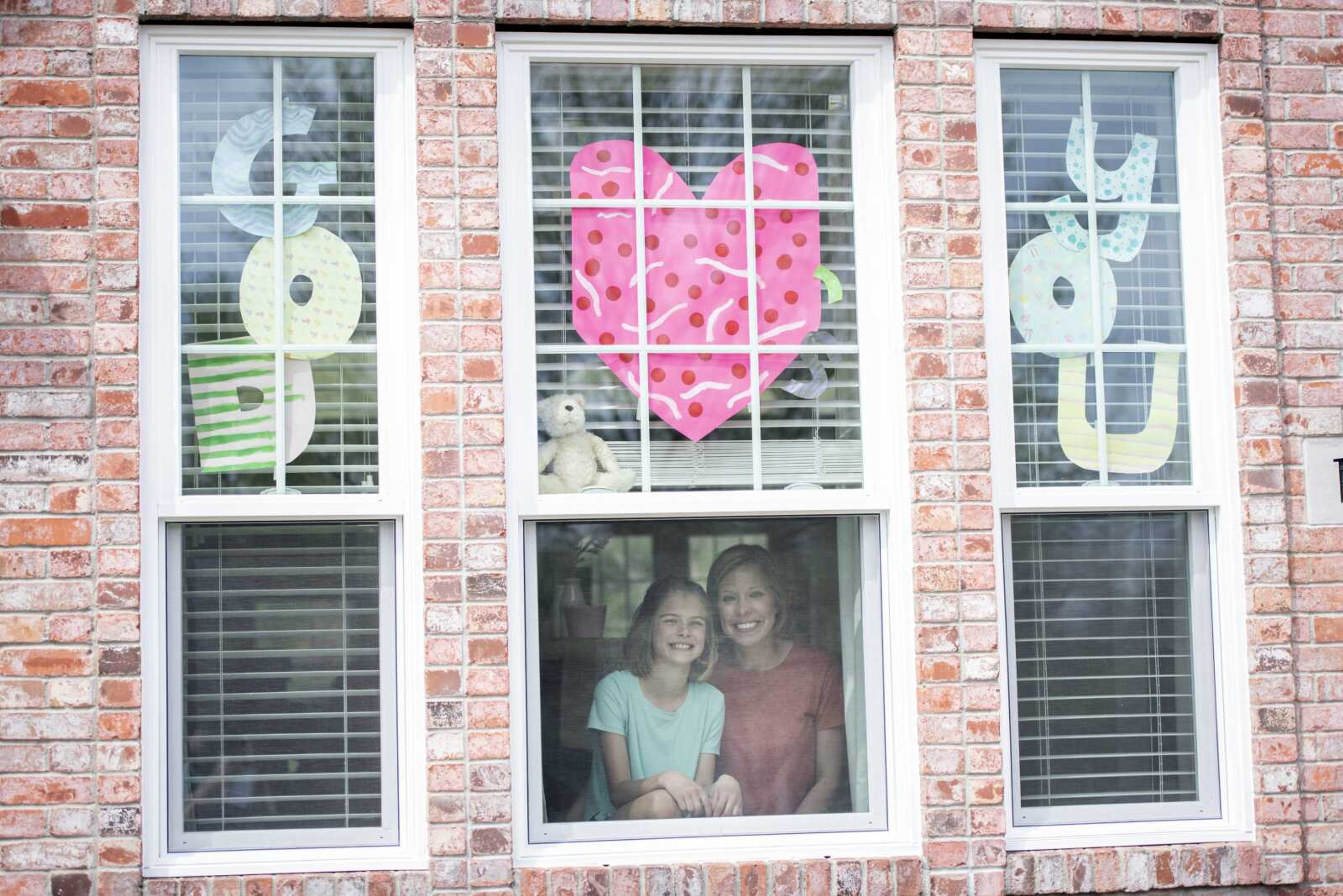 Julie Ogles of Cape Girardeau and her daughter Caroline, 10, pose for a portrait Tuesday at their Cape Girardeau home next to signs Caroline made.