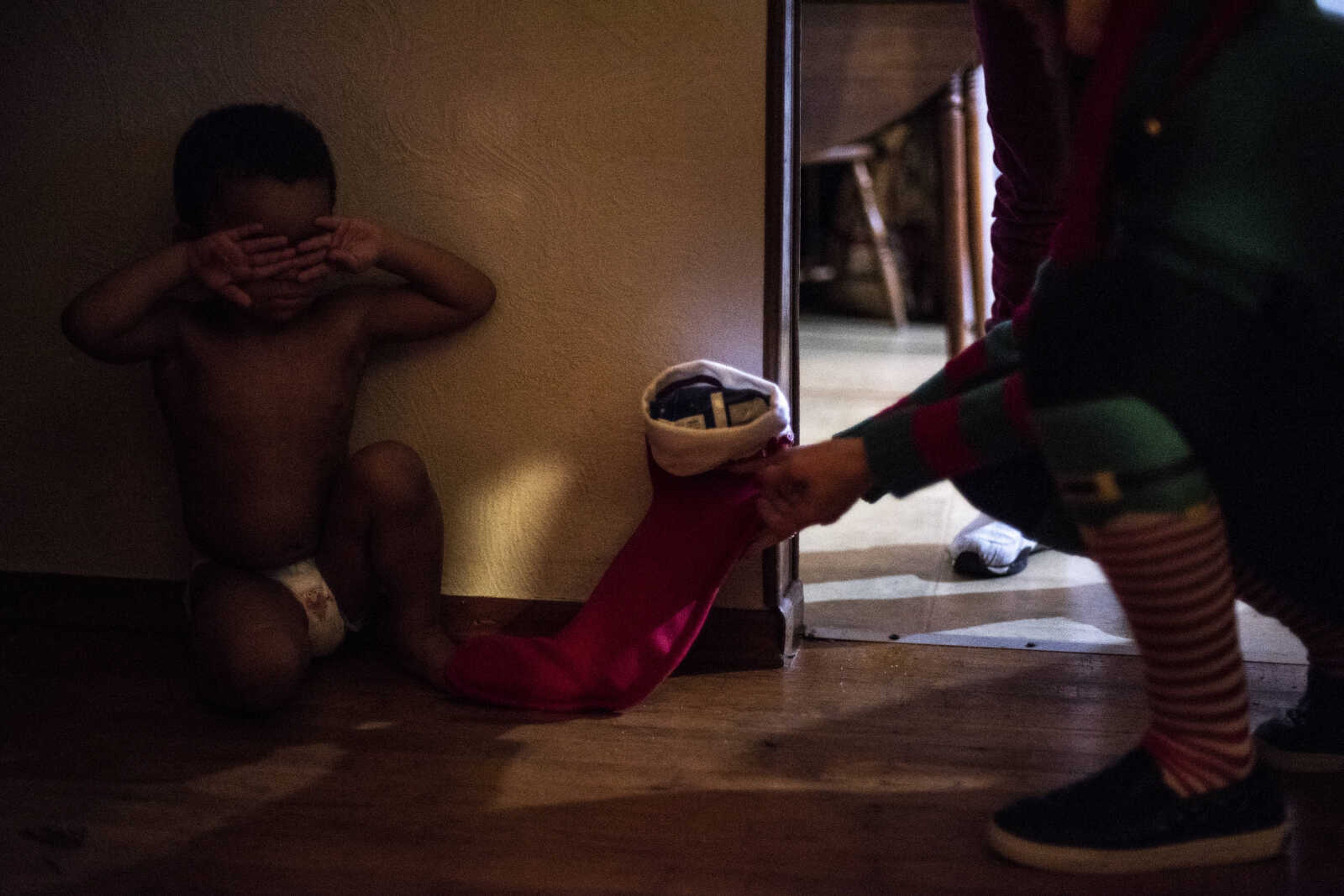 Lazae'vion cries as Jillian O'Connell places a stocking on the ground next to him during the 43rd-annual Toybox toy drive delivery night Thursday, Dec. 20, 2018, in Cape Girardeau.