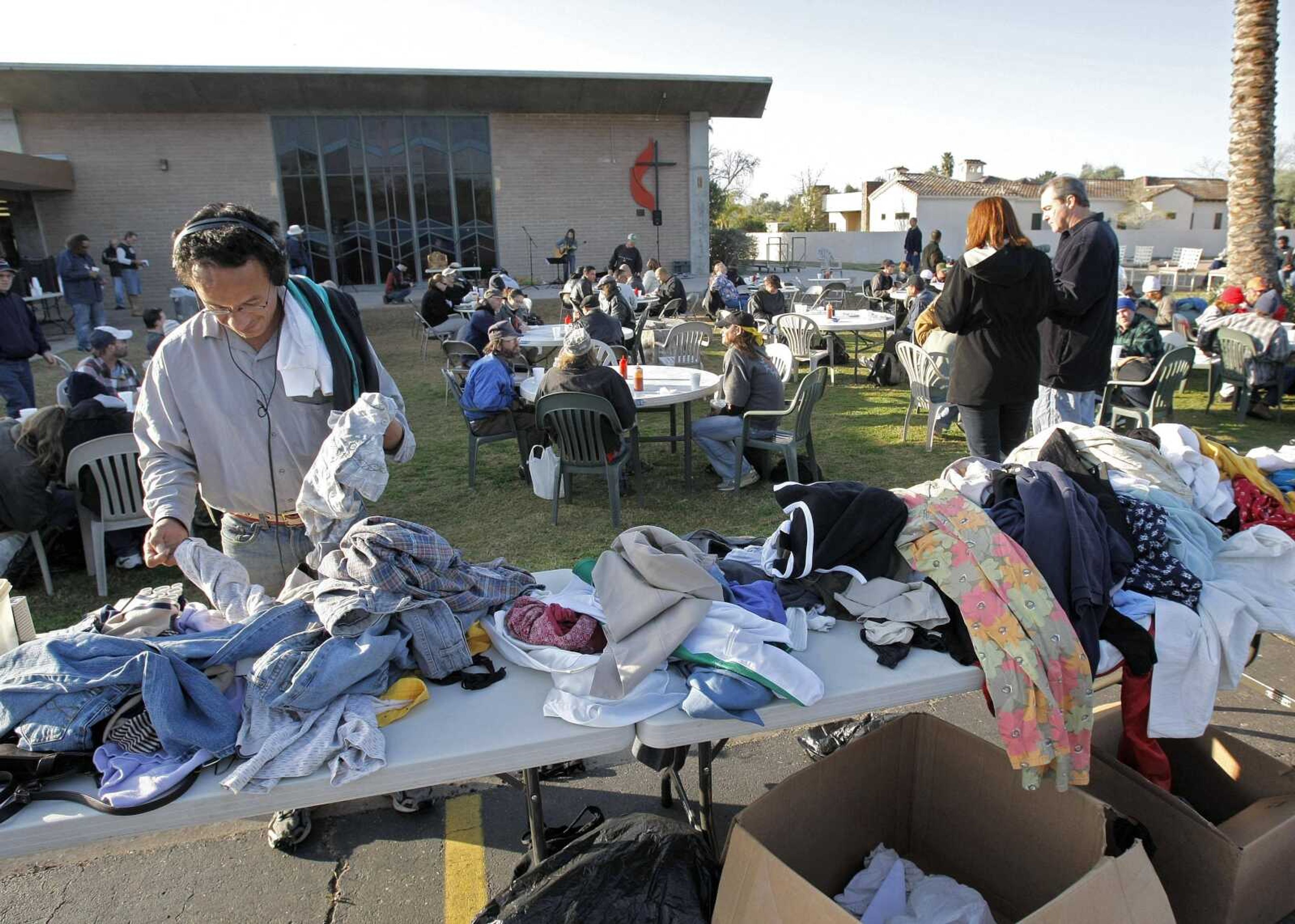 A homeless man looks through donated clothing Feb. 13 at CrossRoads United Methodist Church in Phoenix. (MATT YORK ~ Associated Press)