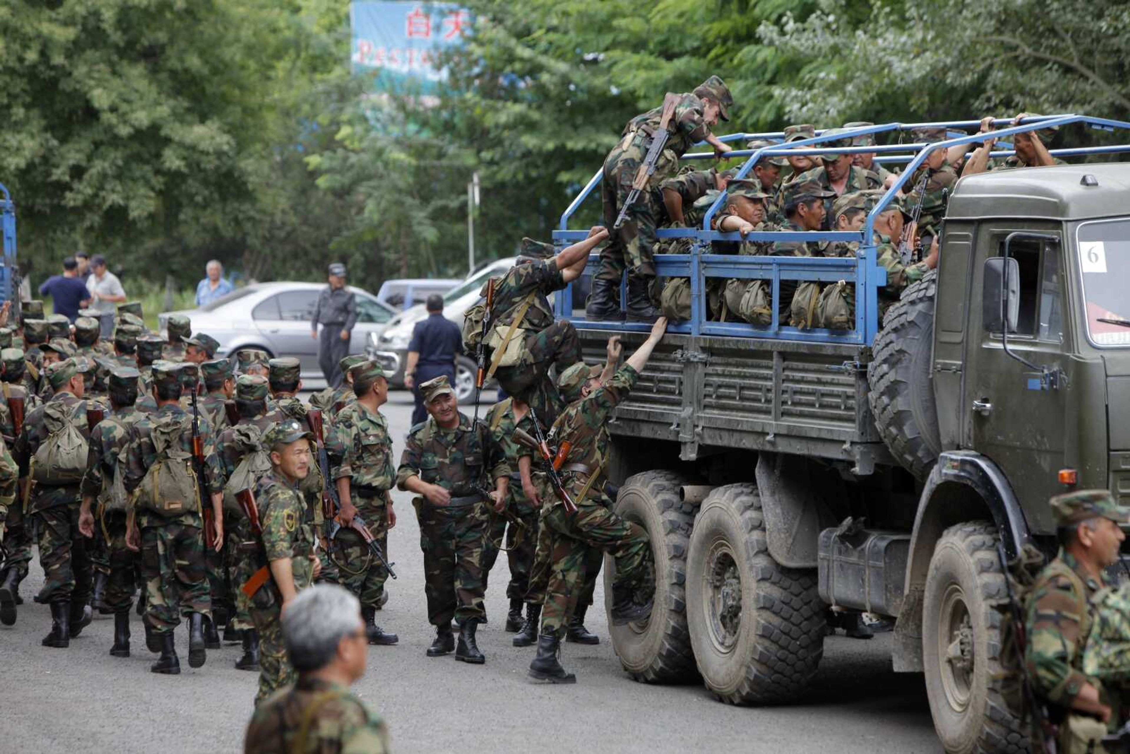 Kyrgyz army soldiers and volunteers climb up on a military truck Wednesday to patrol the outskirts of the southern city of Osh, Kyrgyzstan. (ALEXANDER ZEMLIANICHENKO ~ Associated Press)