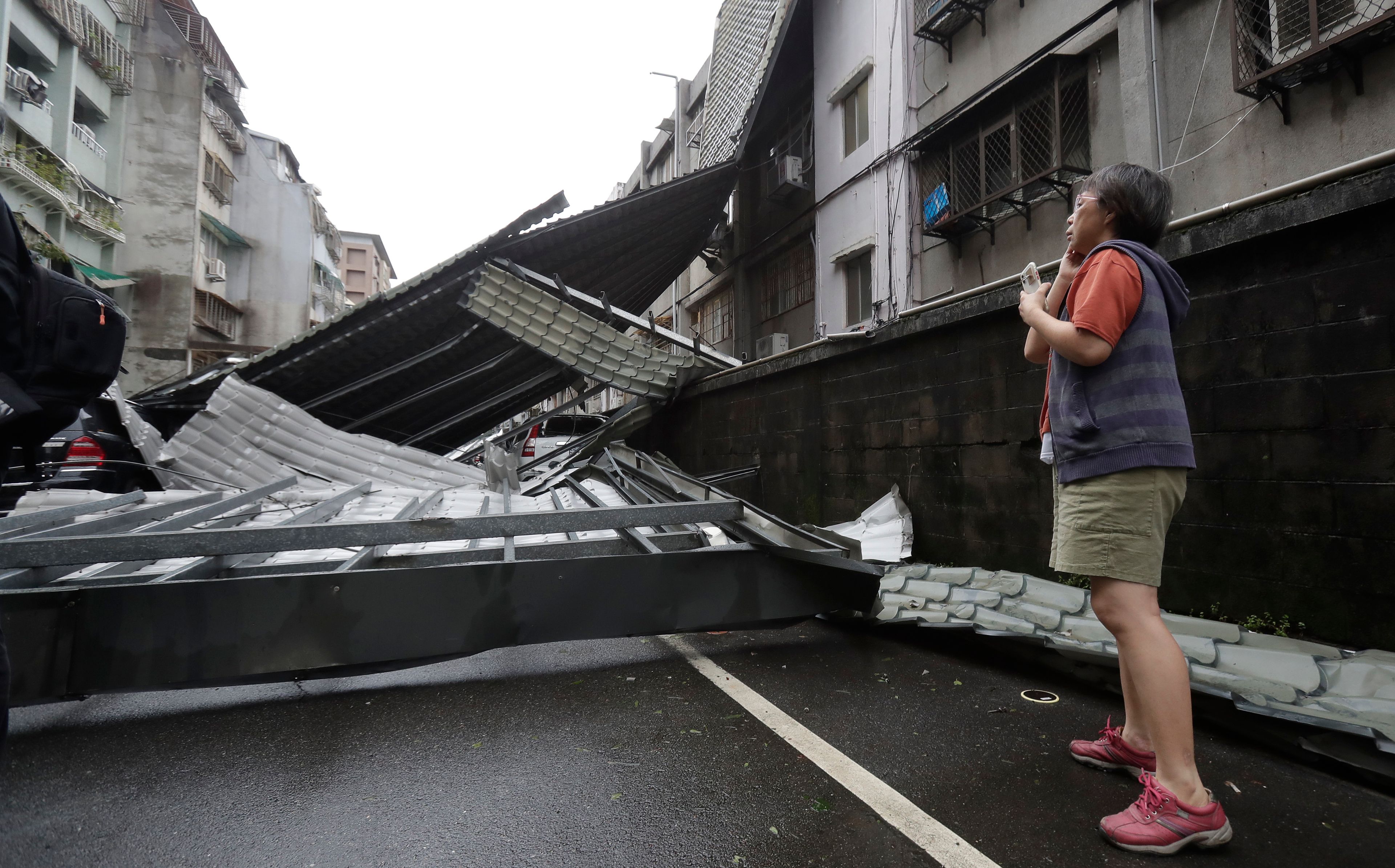 A woman looks at a row of blown roofs destroyed by the wind of Typhoon Kong-rey in Taipei, Taiwan, Friday, Nov. 1, 2024. (AP Photo/Chiang Ying-ying)