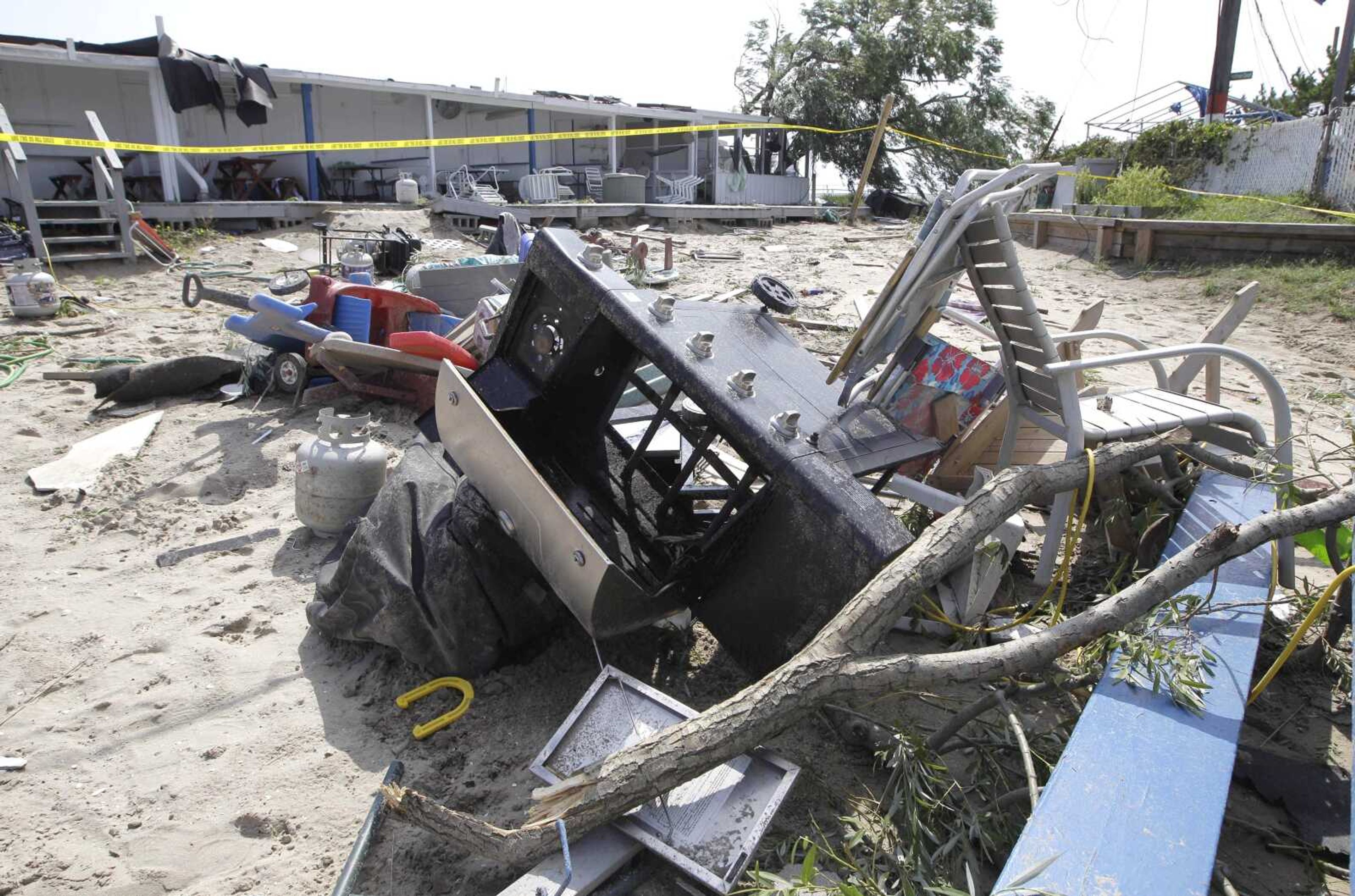 A pile of debris, including a gas barbecue and propane tank, lie in the sand in front of cabanas at the Breezy Point Surf Club, which was damaged during severe weather Saturday in New York. (Kathy Willens ~ Associated Press)