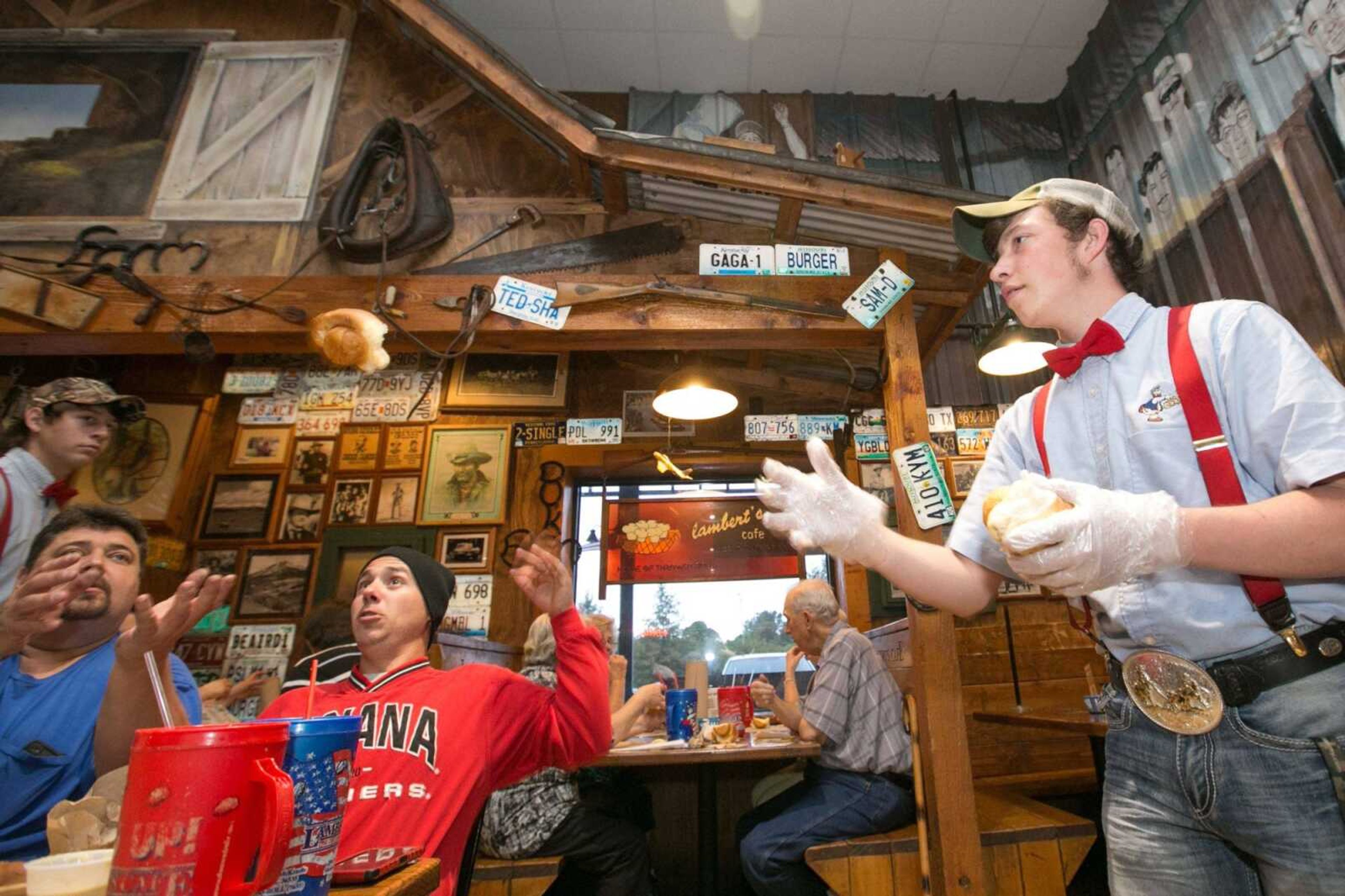 Dayid Hays tosses a hot roll through the air to a diner at Lambert's Cafe in Sikeston in this photo from 2015. Lambert's is marking 80 years in business this month.