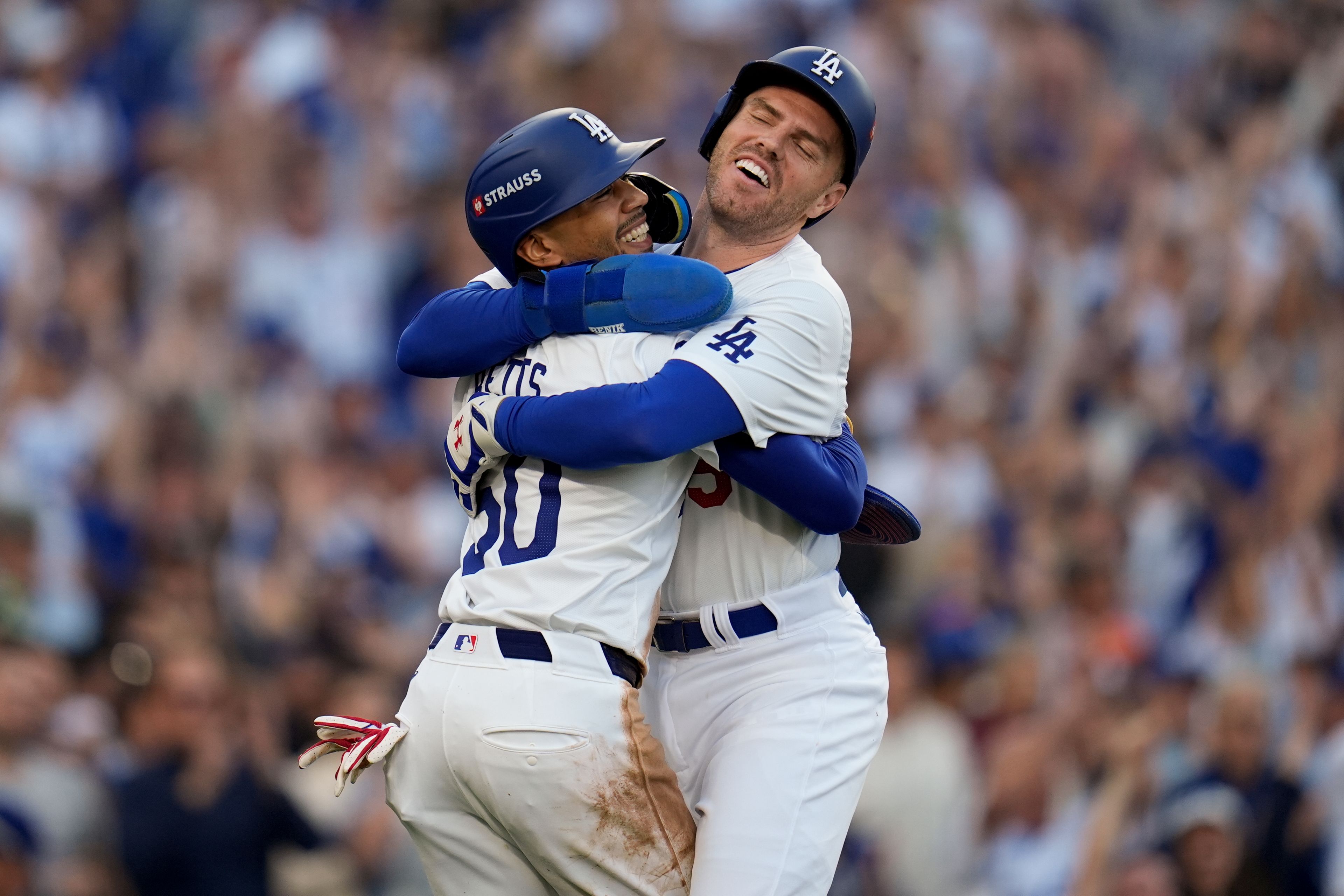 Los Angeles Dodgers' Freddie Freeman, right, and Mookie Betts celebrate after they scored on a single by Max Muncy during the first inning in Game 1 of a baseball NL Championship Series against the New York Mets, Sunday, Oct. 13, 2024, in Los Angeles. (AP Photo/Gregory Bull)