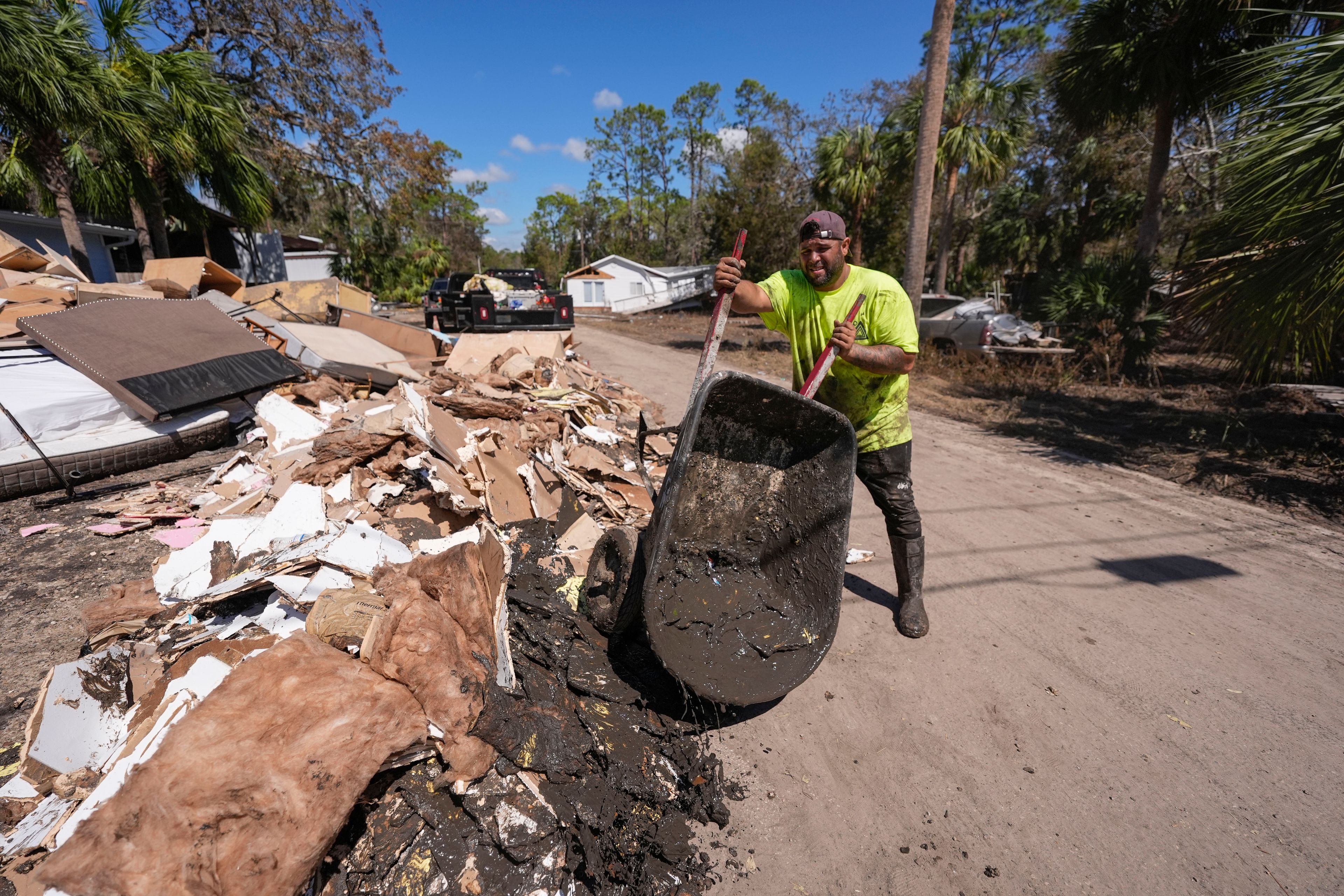 Jose Salazar dumps debris as he helps gut a property that took on a storm surge in the aftermath of Hurricane Helene, in Steinhatchee, Fla., Sunday, Sept. 29, 2024. (AP Photo/Gerald Herbert)