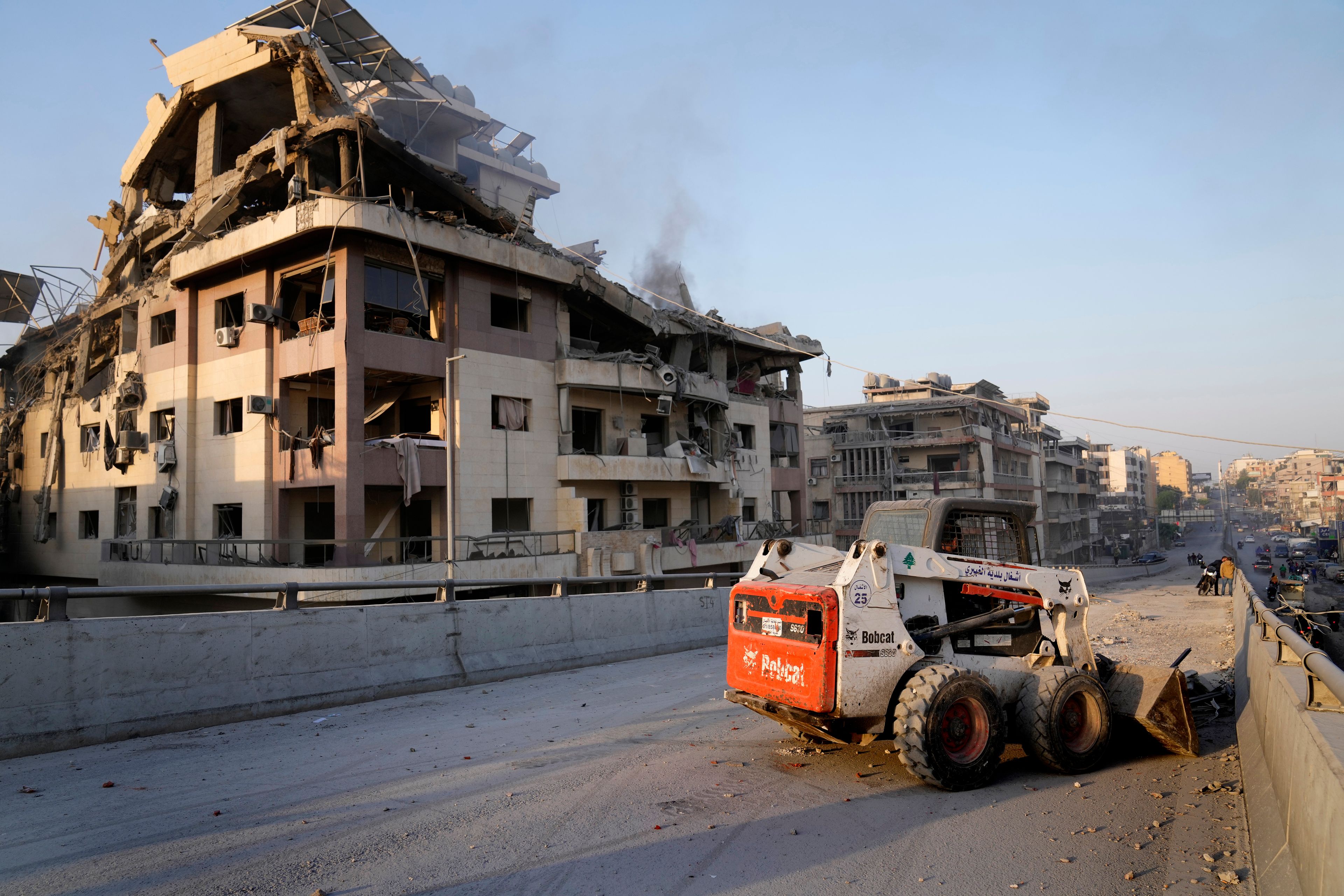 A municipality worker uses a skid steer loader to reopen a bridge closed by the rubble of a destroyed building that was hit by an Israeli airstrike on Dahiyeh, in the southern suburb of Beirut, Lebanon, Friday, Nov. 1, 2024. (AP Photo/Hussein Malla)