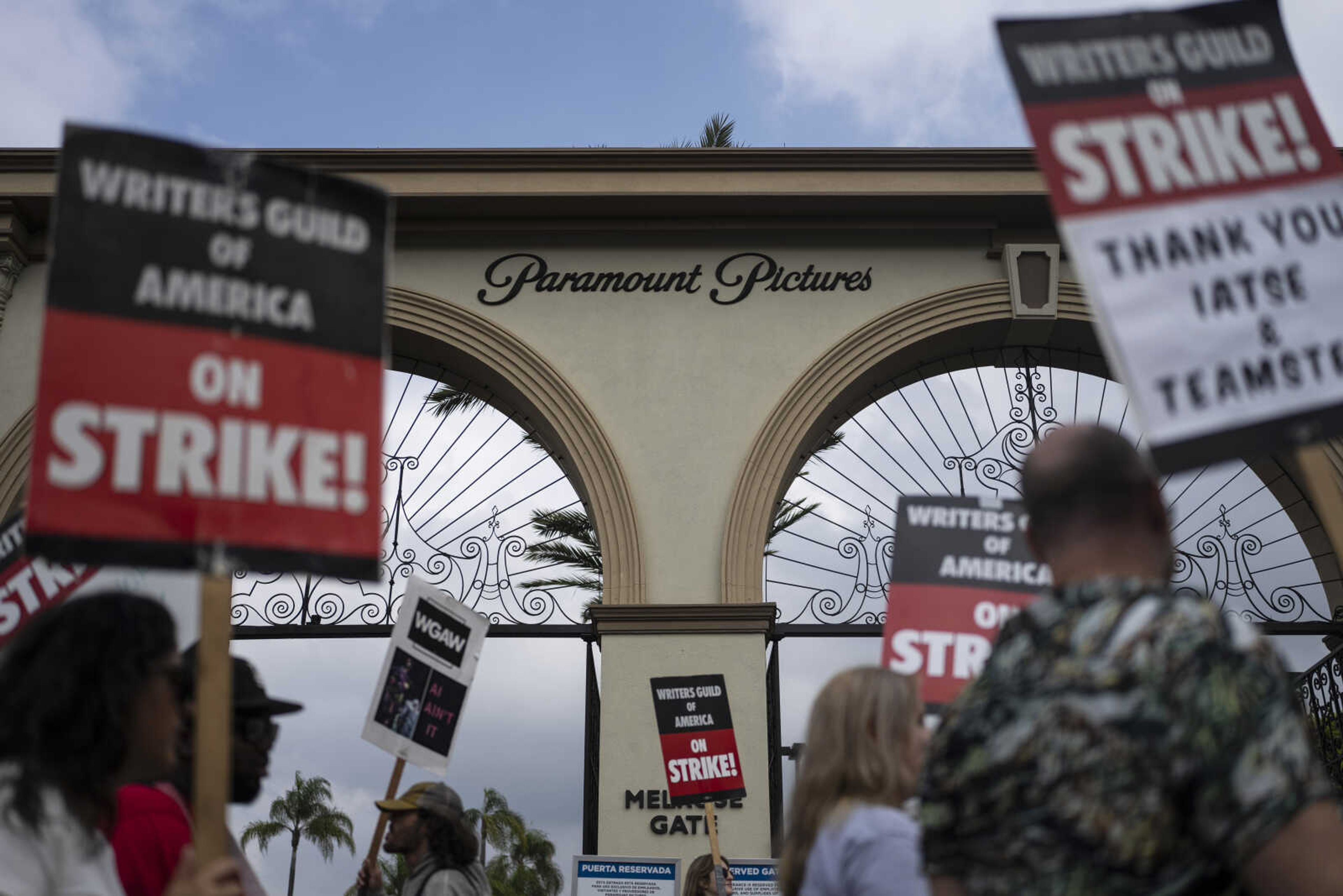 Demonstrators walk with signs during a rally Thursday outside the Paramount Pictures Studio in Los Angeles. A tentative deal was reached Sunday to end Hollywood's writers strike after nearly five months.