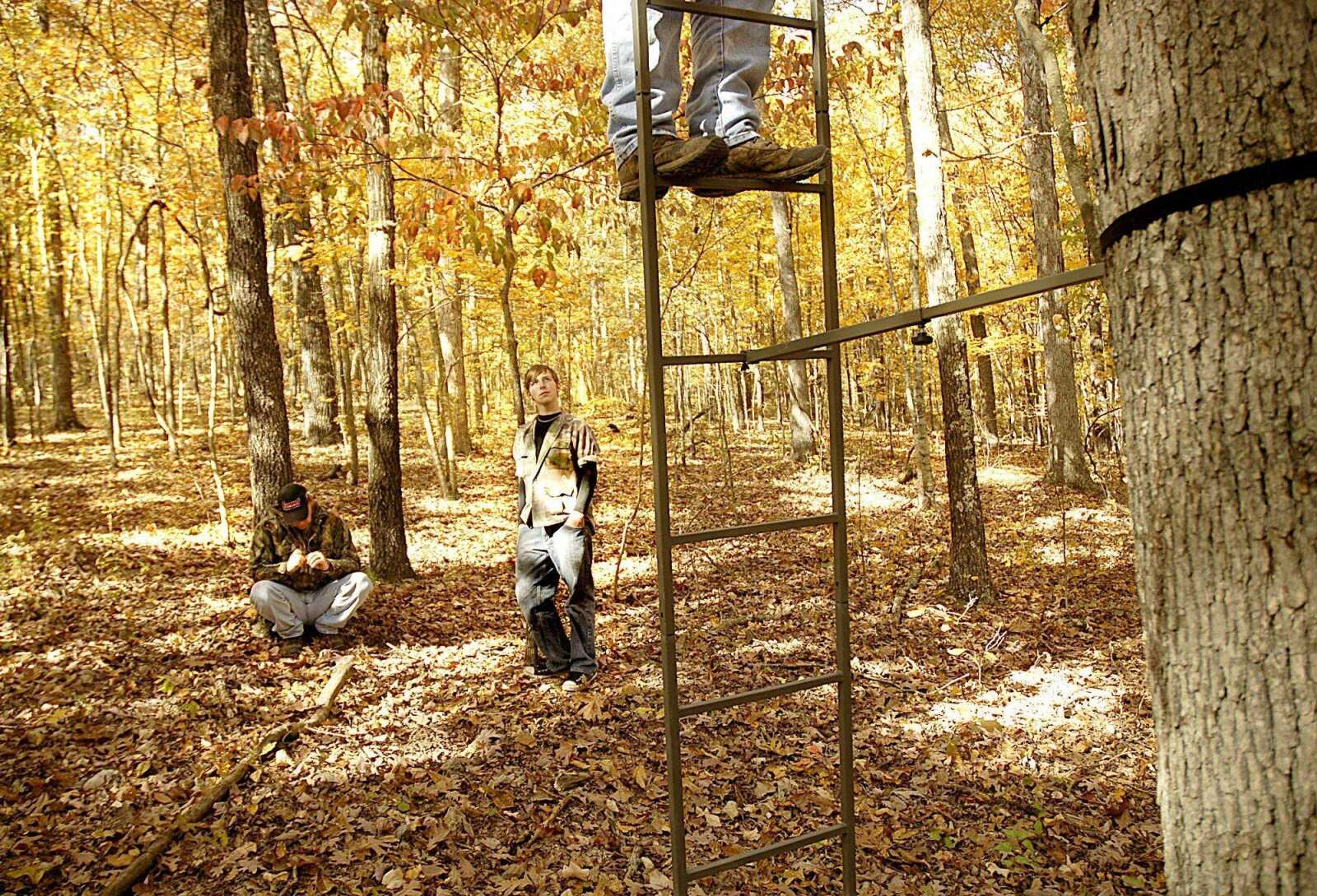 Troy and Tyler Mayeux stayed on the ground as Tom Barrows climbed up a tree stand Friday to attach a cushion as the group prepared for their deer hunt. (Aaron Eisenhauer)