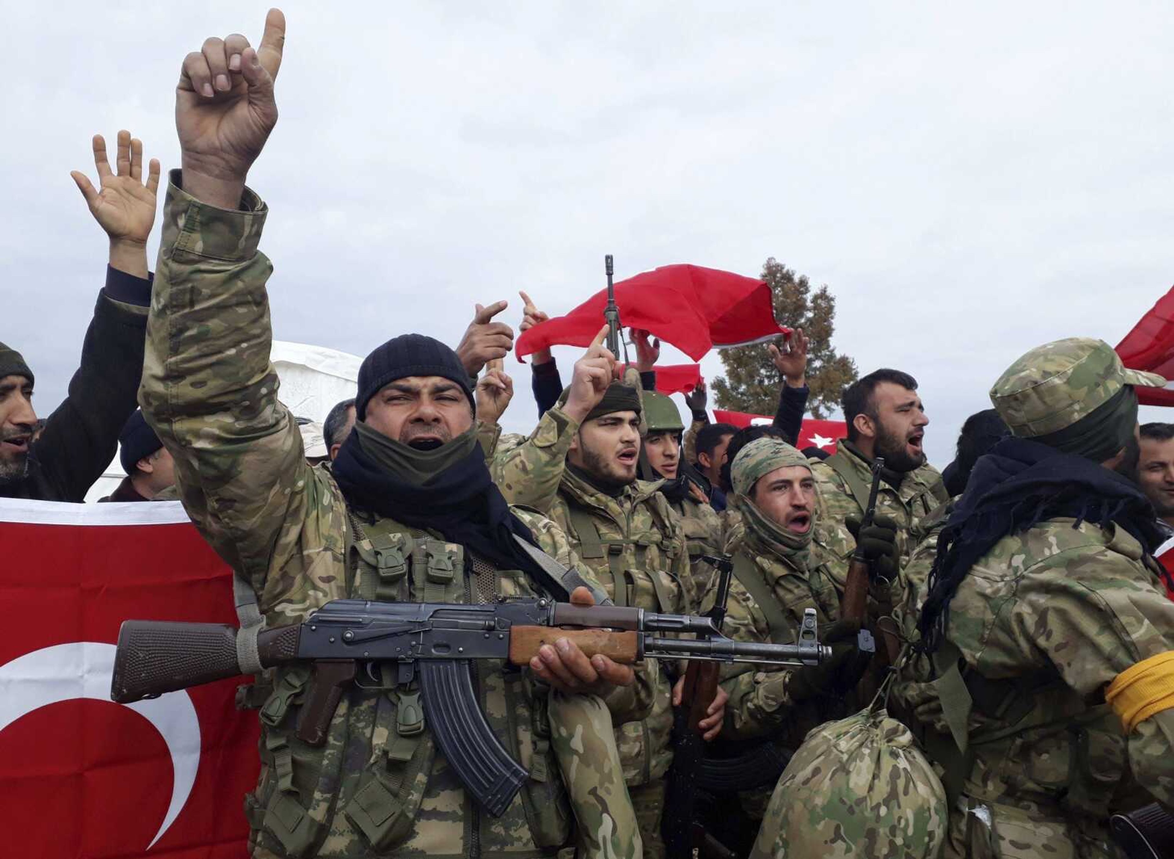 Turkey-backed Free Syrian Army fighters shout slogans before heading toward the Syrian border Sunday. Turkish troops and Syrian opposition forces attacked a Kurdish enclave in northern Syria on Sunday in their bid to drive from the region a U.S.-allied Kurdish militia.