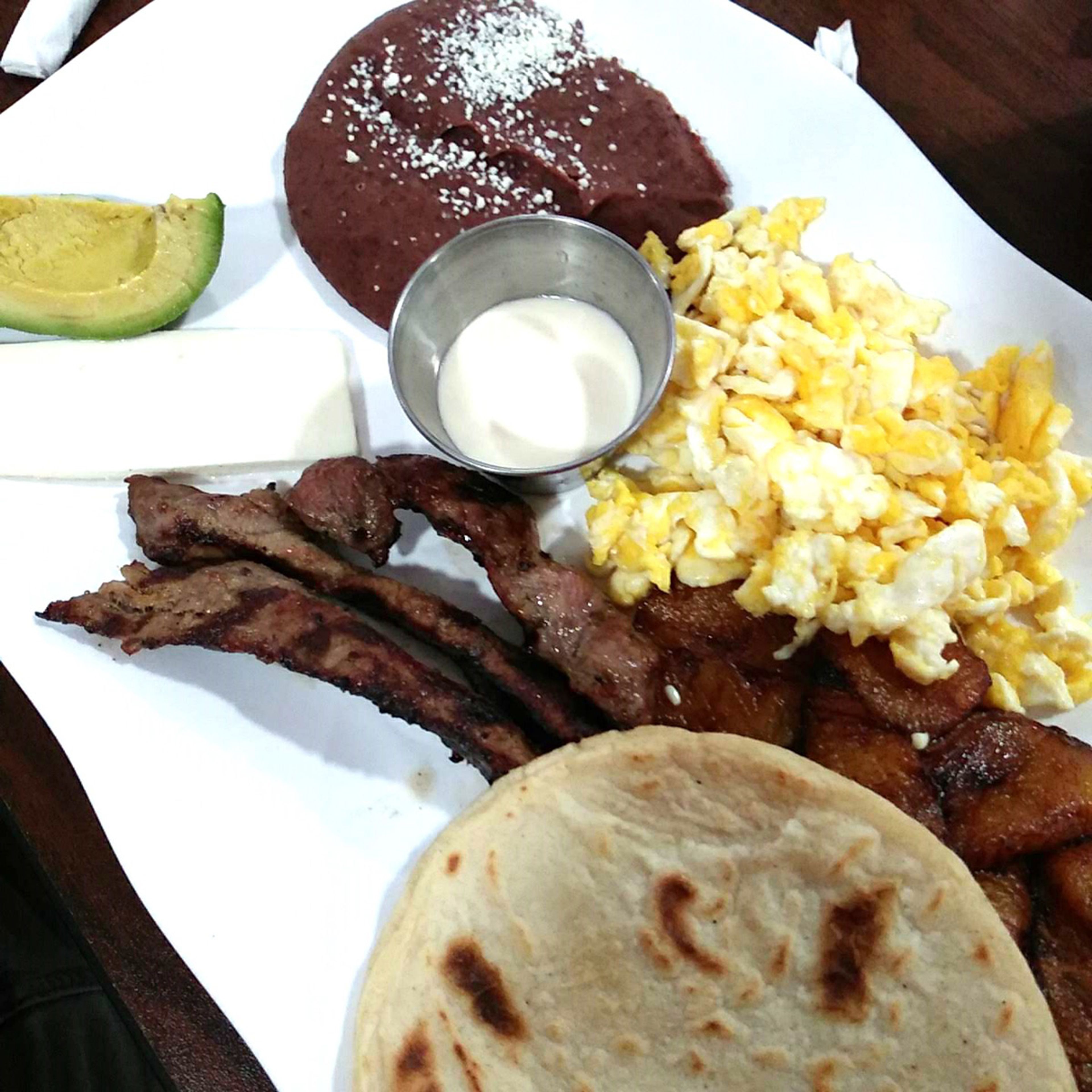 Desayuno Catracho Especial, with homemade tortillas, mouthwatering marinated grilled steak, and made-from-scratch black refried beans.