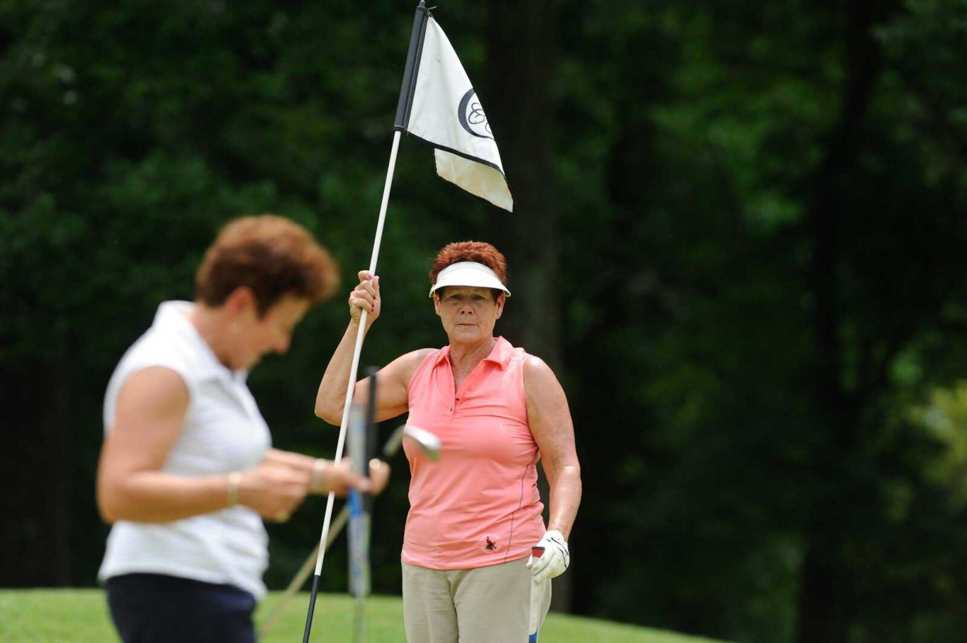 Dee Lee holds a pin flag while Jan Reel sets up for a putt on the 11th hole Wednesday, July 20, 2016, during the Lassies Classic at the Cape Girardeau Country Club.