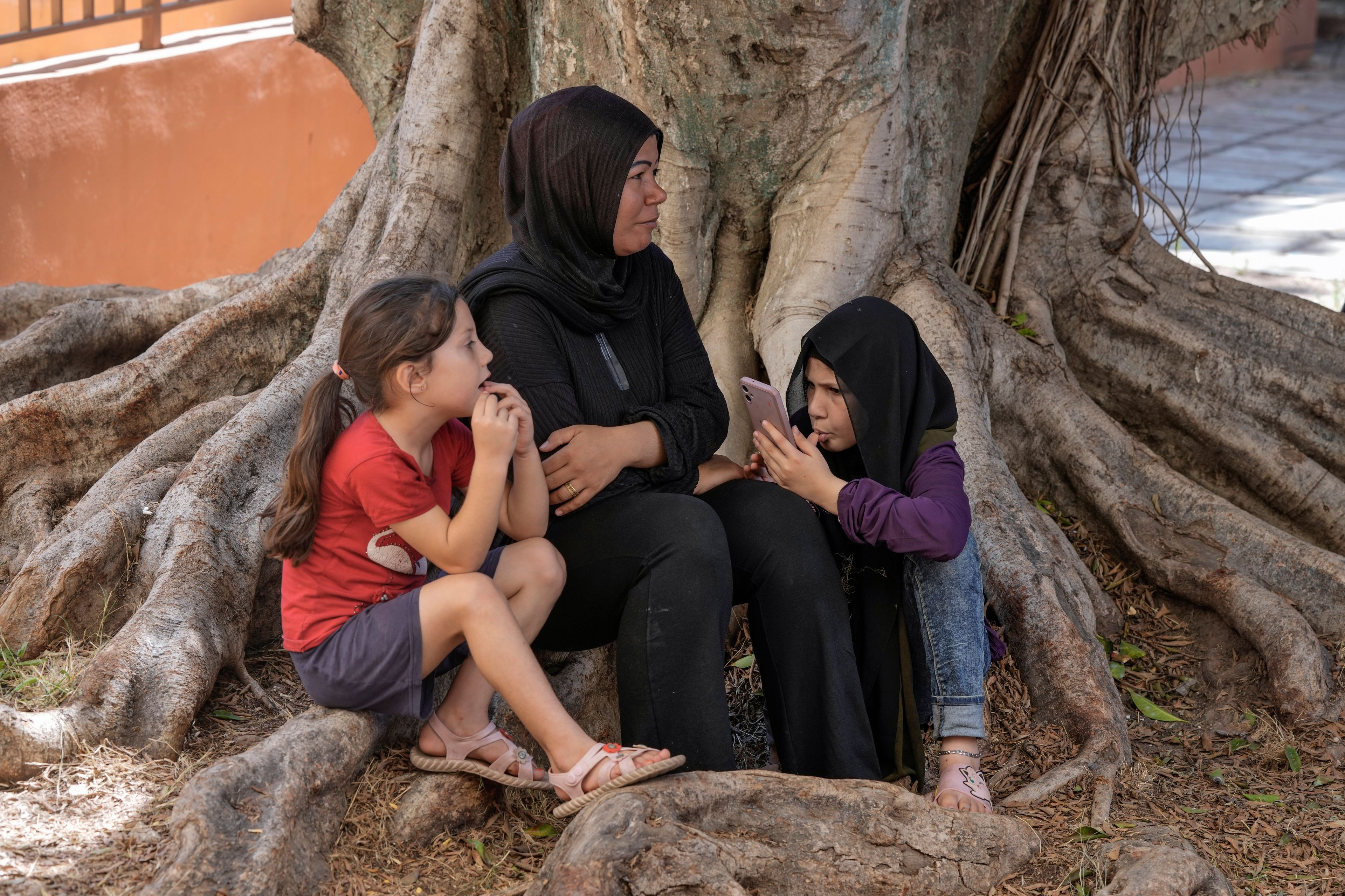 A displaced woman sits with her daughters at a vocational training center run by the U.N. agency for Palestinian refugees, or UNRWA, in the southern town of Sebline, south of Beirut, Lebanon, Friday, Oct. 4, 2024, after fleeing the Israeli airstrikes in the south. (AP Photo/Bilal Hussein)