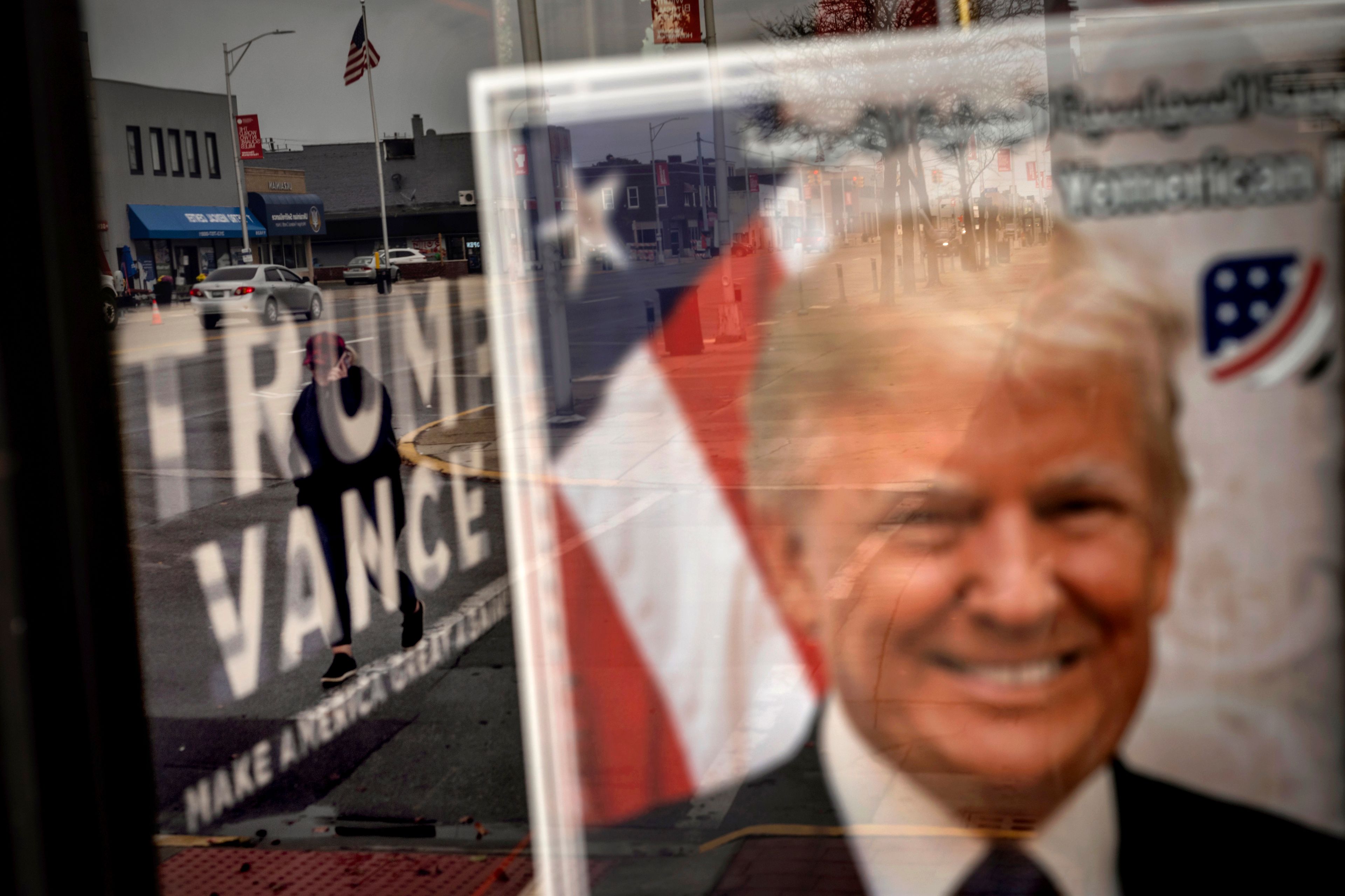 An image of Republican presidential nominee former President Donald Trump hangs in the window of a campaign office as a pedestrian passes by Monday, Nov. 4, 2024, in Hamtramck, Mich. (AP Photo/David Goldman)