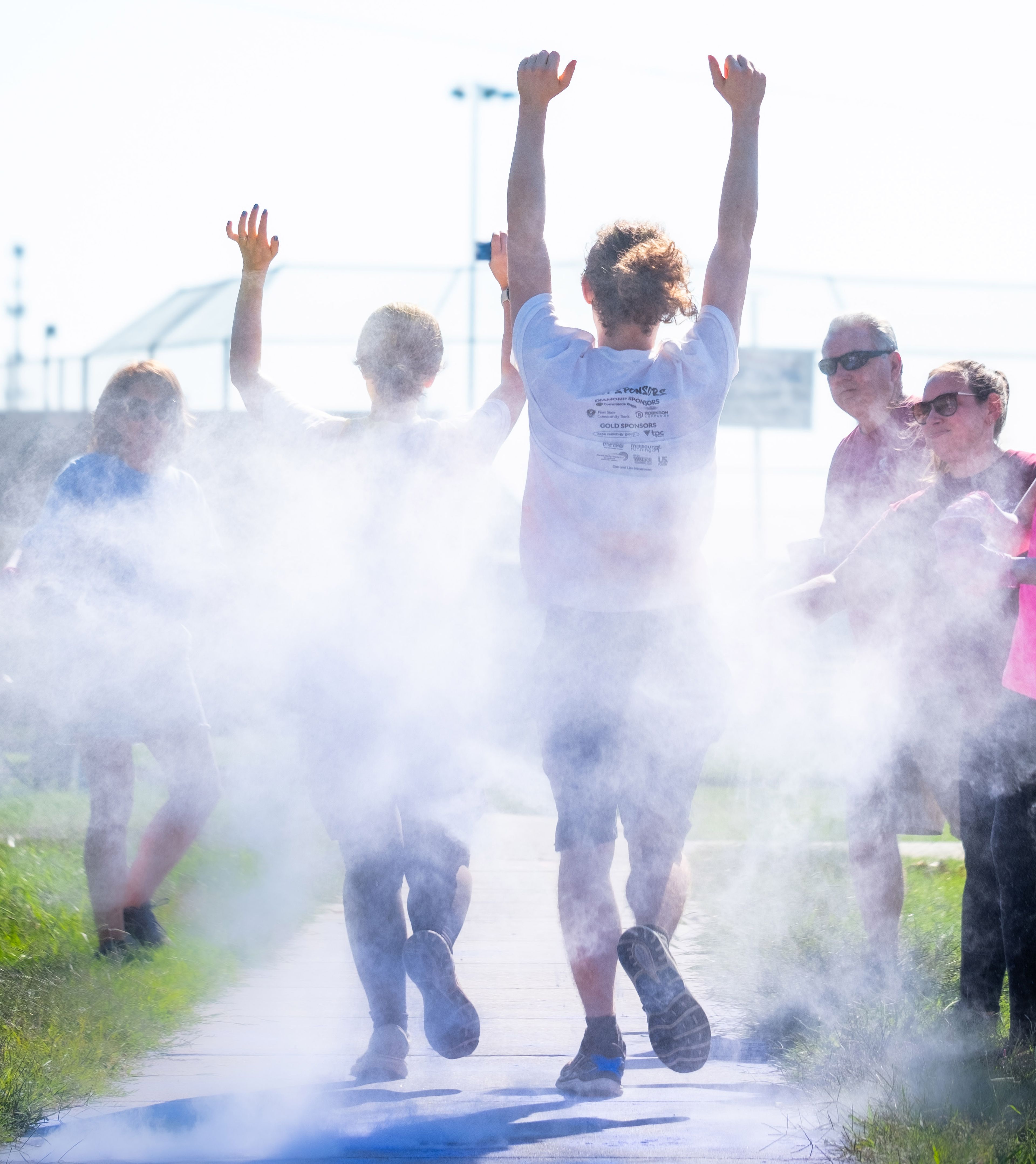 Children laugh as they run through clouds of colored dust.
