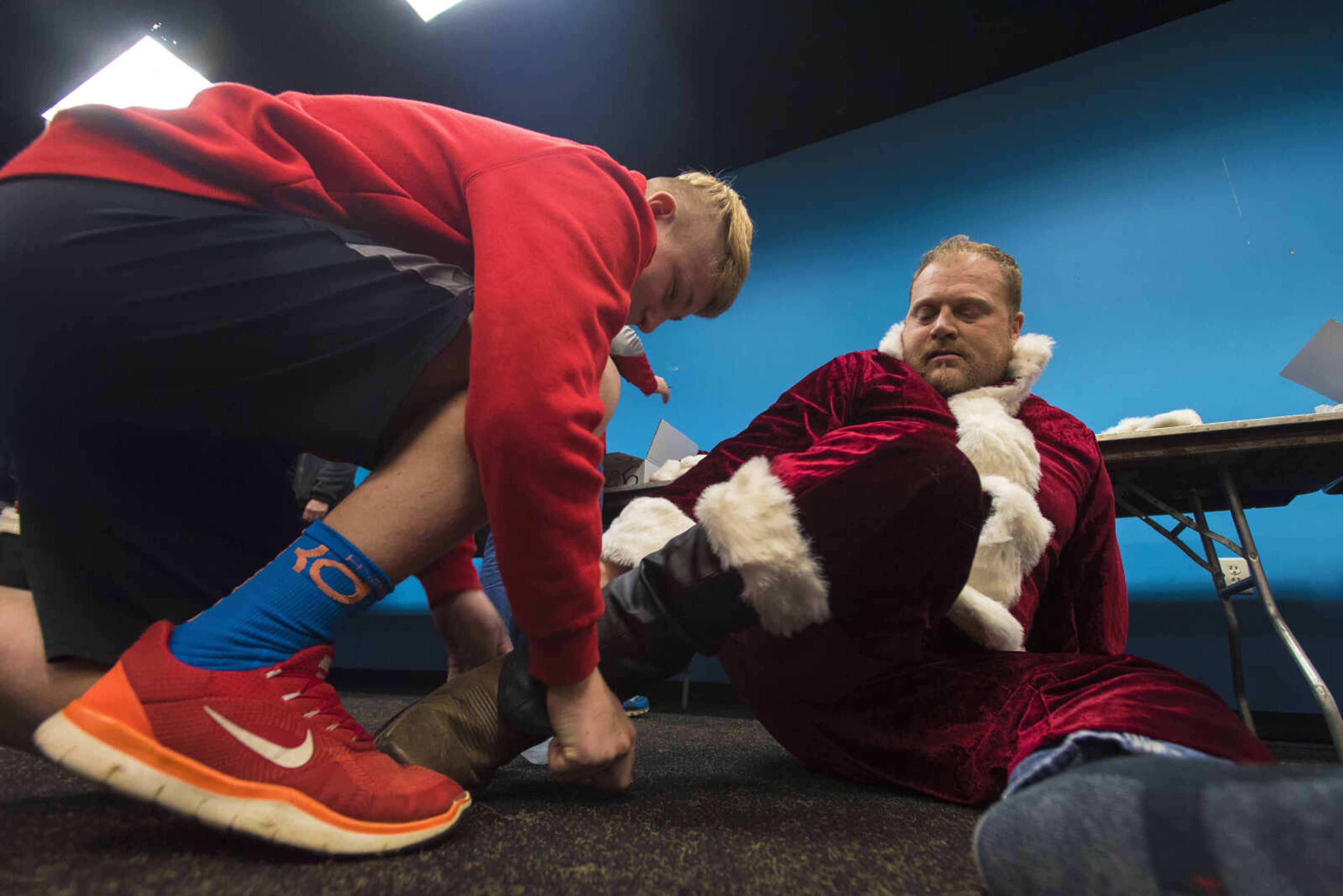 Ethan Jackson, 12, helps out his dad Jamie Jackson put on his Santa boots during the Jaycee Toybox delivery on Thursday, Dec. 21, 2017, in Cape Girardeau.