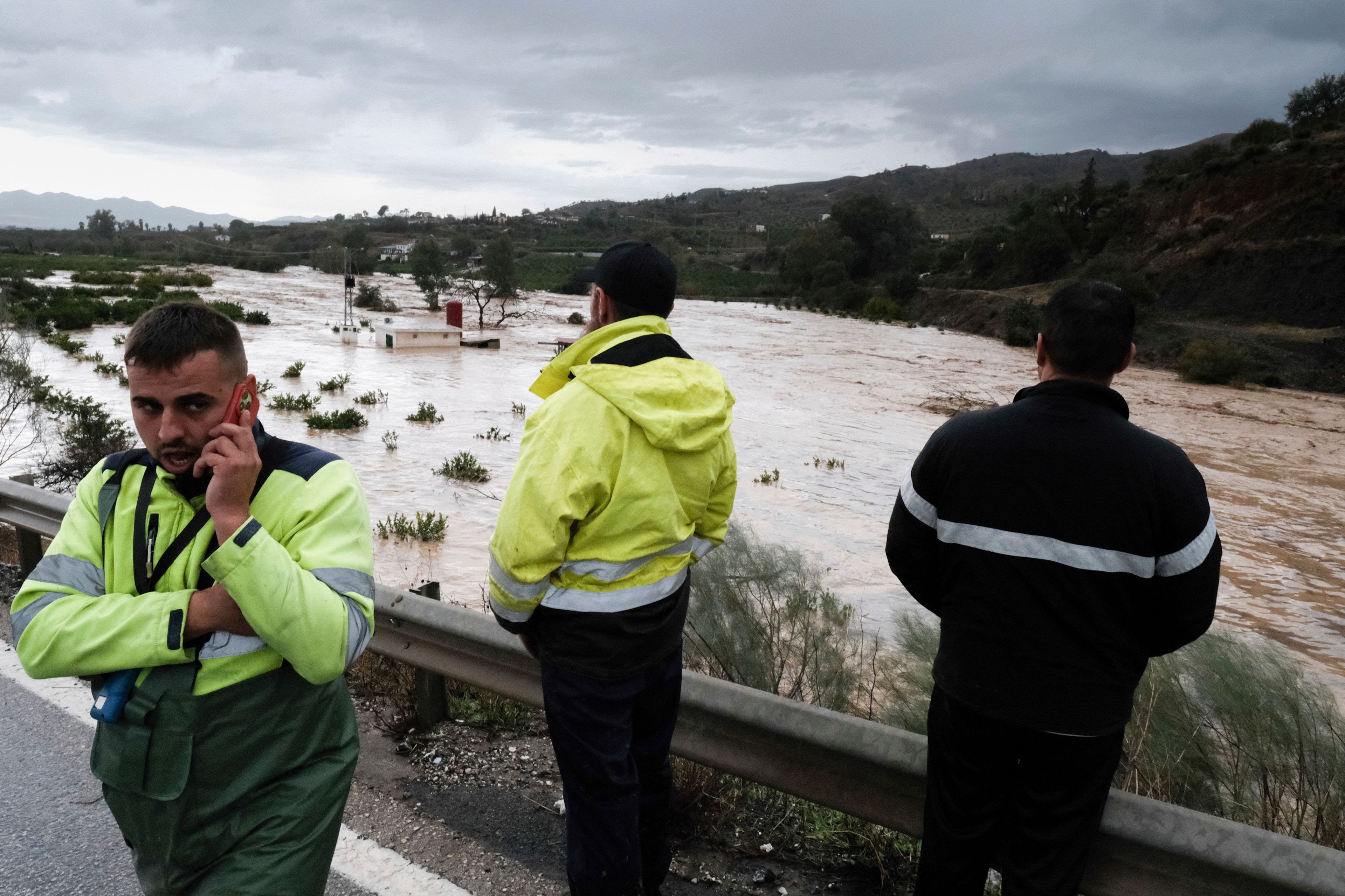 People look at the rising river, after floods preceded by heavy rains caused the river to overflow its banks in the town of Alora, Malaga, Spain, Tuesday, Oct. 29, 2024. (AP Photo/Gregorio Marrero)