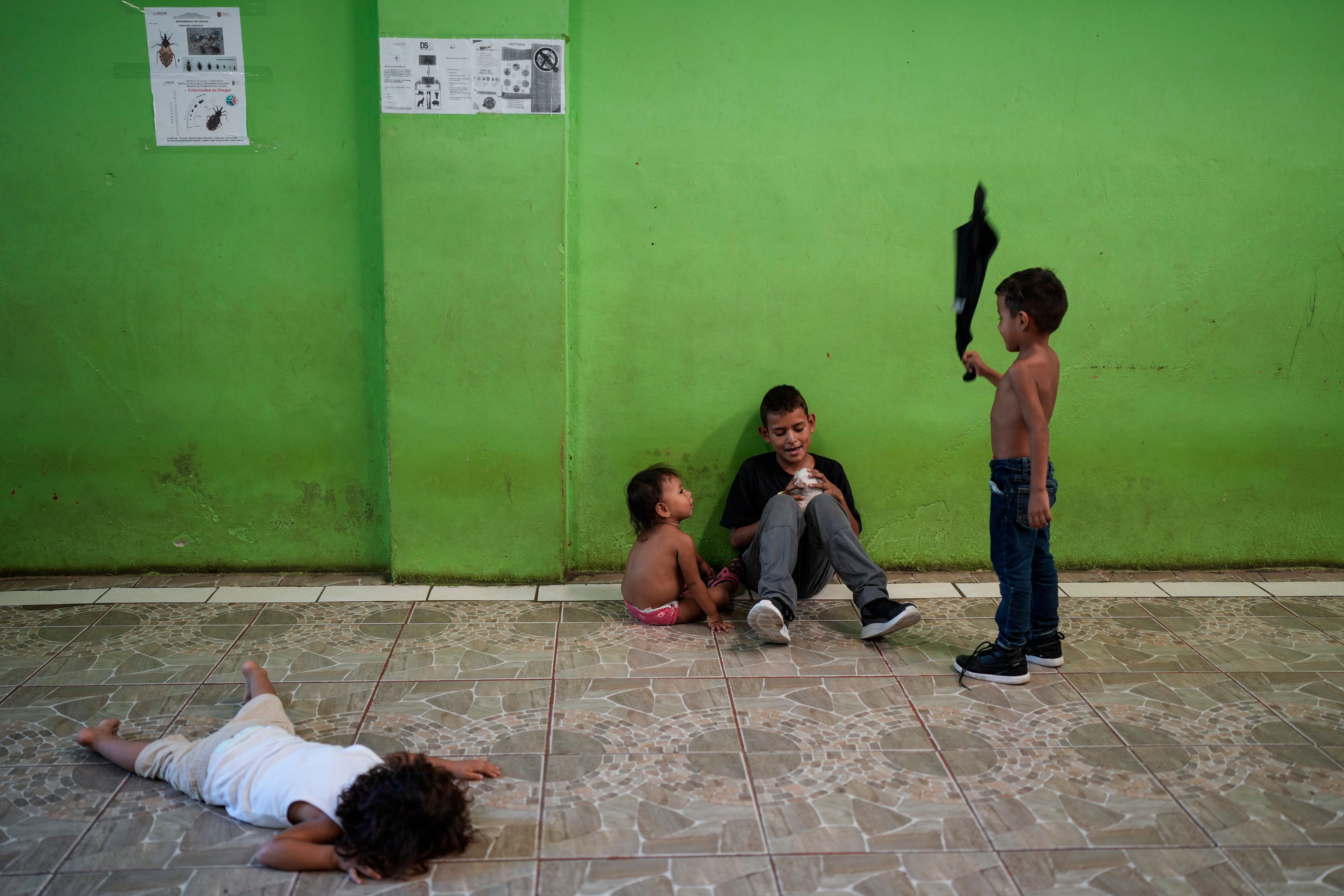 Honduran migrant Danis Palma, second from right, plays with a cat in a shelter in Tapachula, Mexico, Monday, Oct. 28, 2024. (AP Photo/Matias Delacroix)