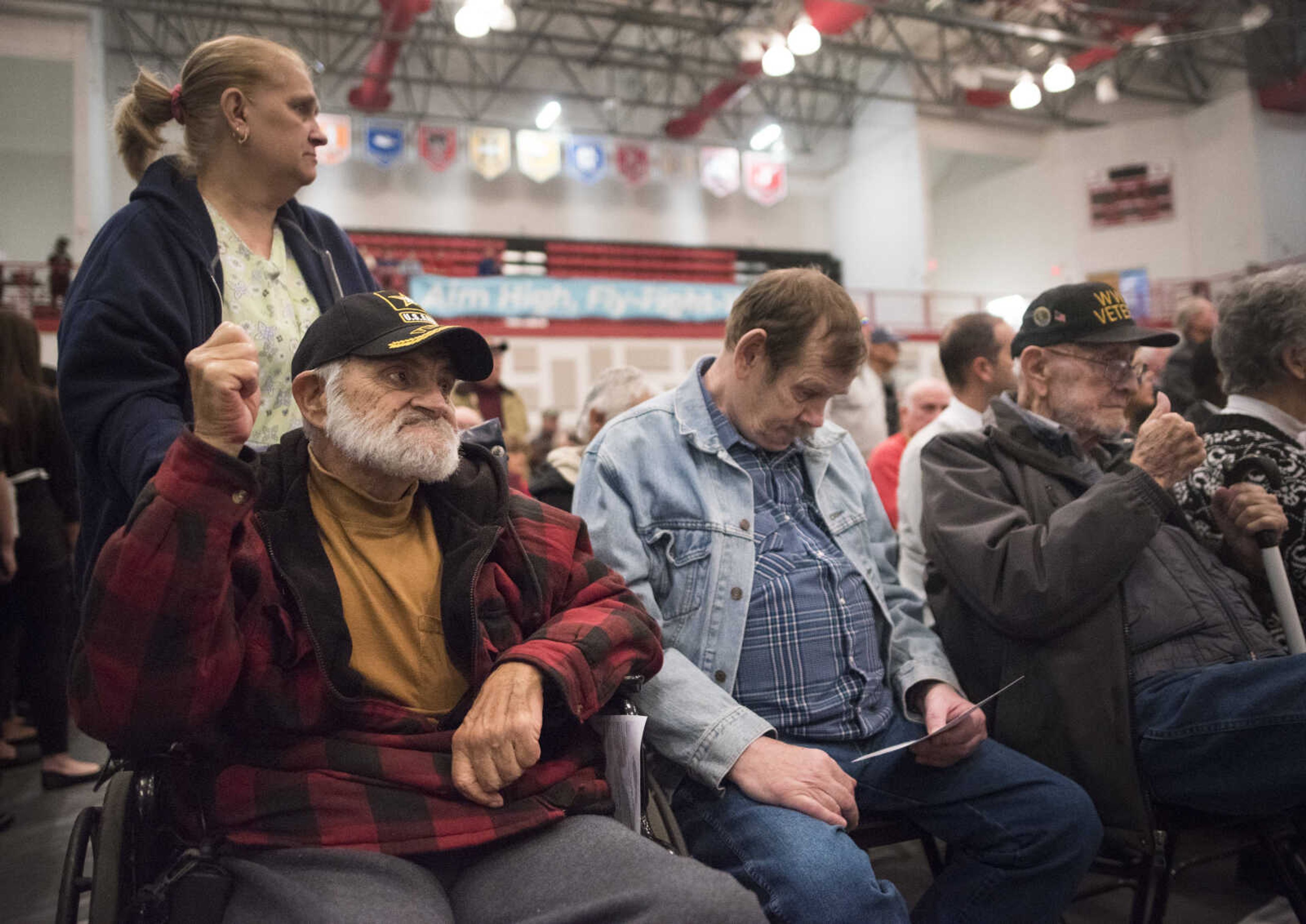 Army veterans Dan Huffman, front left, and Loomis "Jock" Brown of Whitewater, far right, wave their fists to the beat of  "The Caissons Go Rolling Along" while sitting with retired Marine Bob Tucker, center, at an assembly to honor veterans Monday, Nov. 11, 2019, at Jackson High School. Brown, a World War II veteran, served in active duty from 1943 to 1947, Huffman served in active duty from 1973 to 1976.