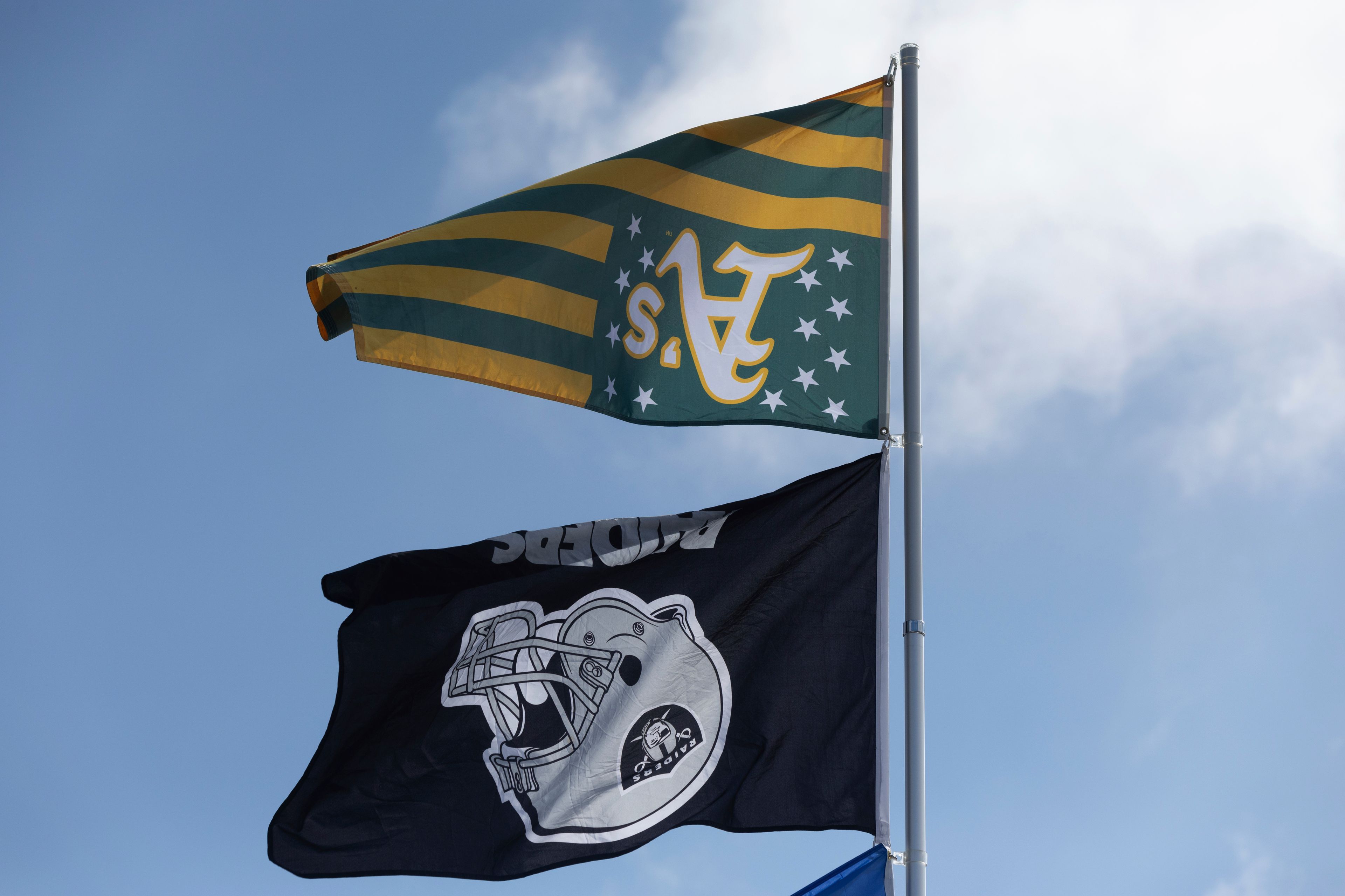 An Oakland Athletics and Raiders flags fly upside down outside the Oakland Coliseum before a baseball game between the Oakland Athletics and the Texas Rangers Thursday, Sept. 26, 2024, in Oakland, Calif. (AP Photo/Benjamin Fanjoy)