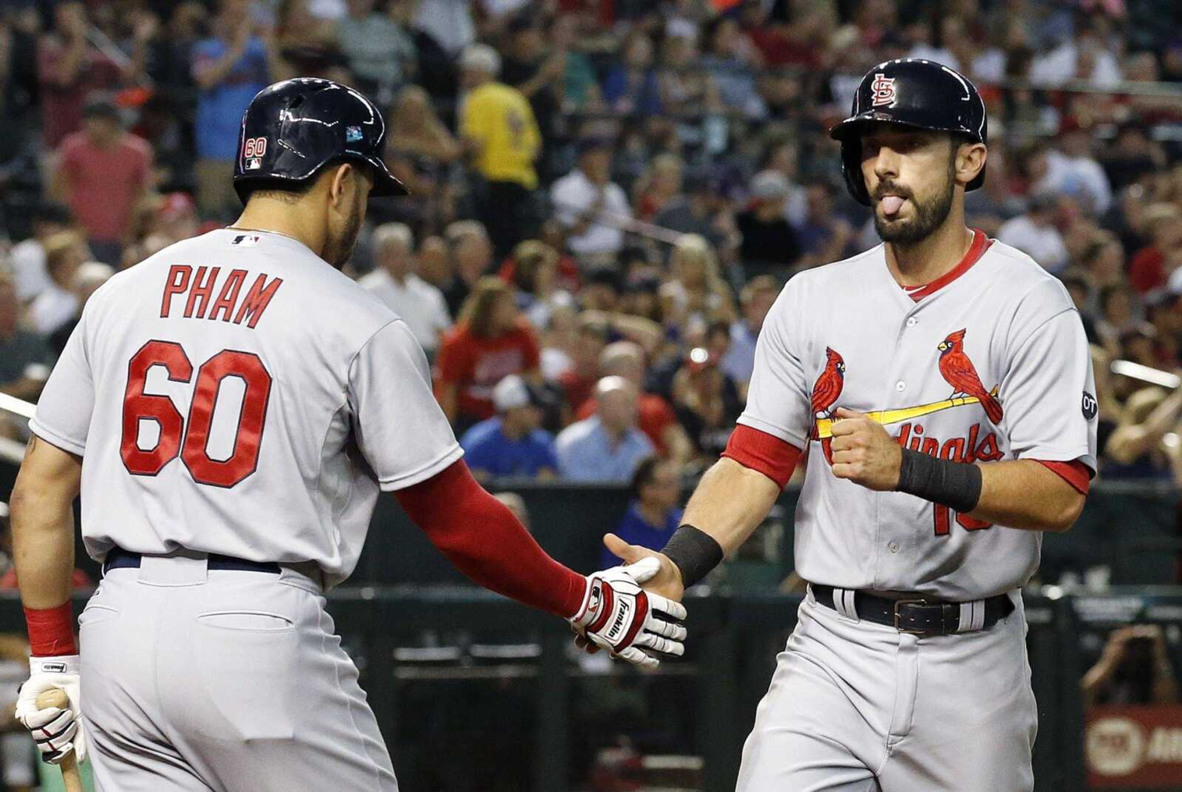 St. Louis Cardinals' Matt Carpenter, right, sticks out his tongue as he shakes hands with Thomas Pham, LEFT, after Carpenter hit a home run against the Arizona Diamondbacks during the third inning of a baseball game Monday, Aug. 24, 2015, in Phoenix. (AP Photo/Ross D. Franklin)