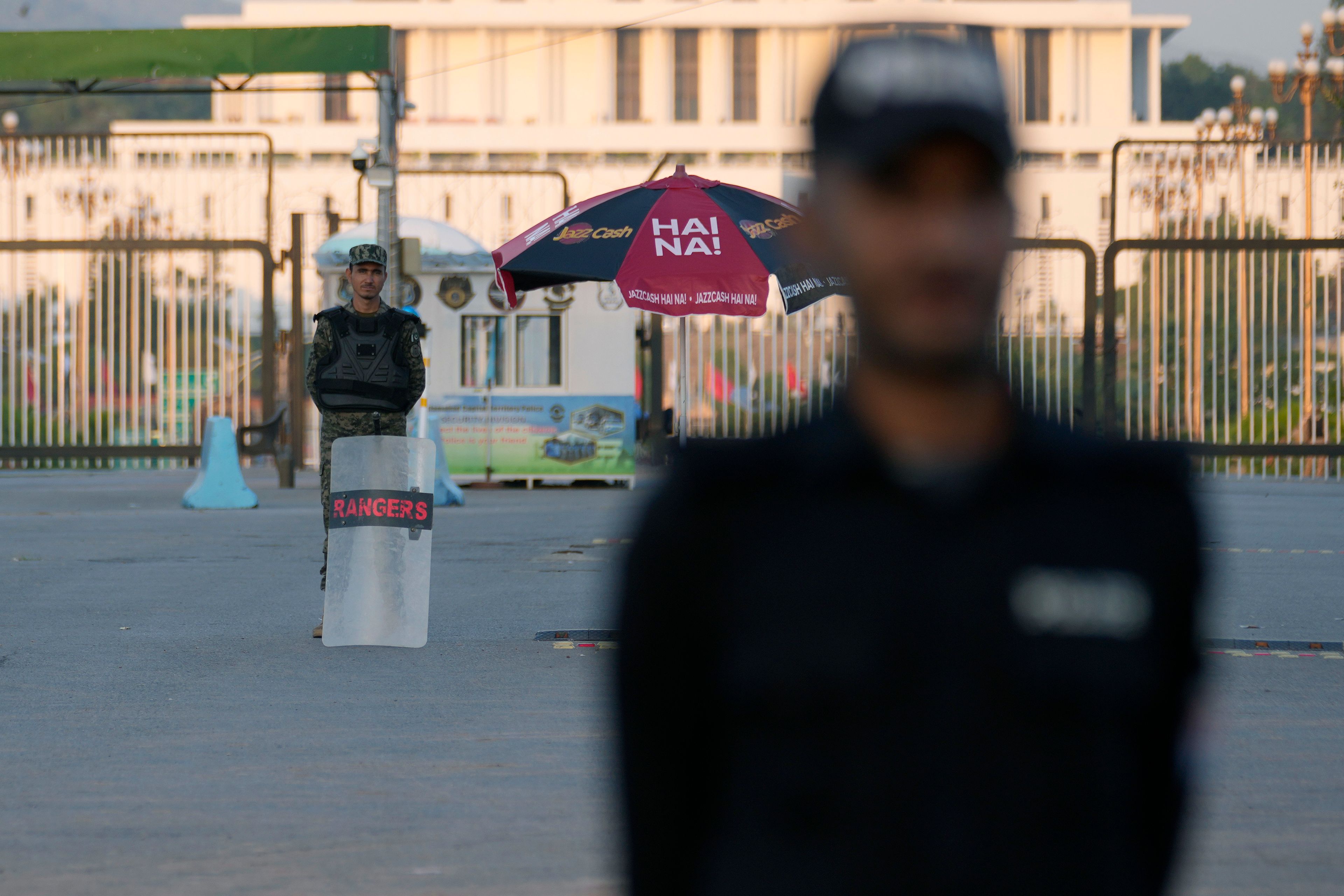 A police officer and a paramilitary soldier stand guard at a barricaded road leading to Presidency, in background, and to the venue of the upcoming Shanghai Cooperation Organization (SCO) summit in Islamabad, Pakistan, Sunday, Oct. 13, 2024. (AP Photo/Anjum Naveed)