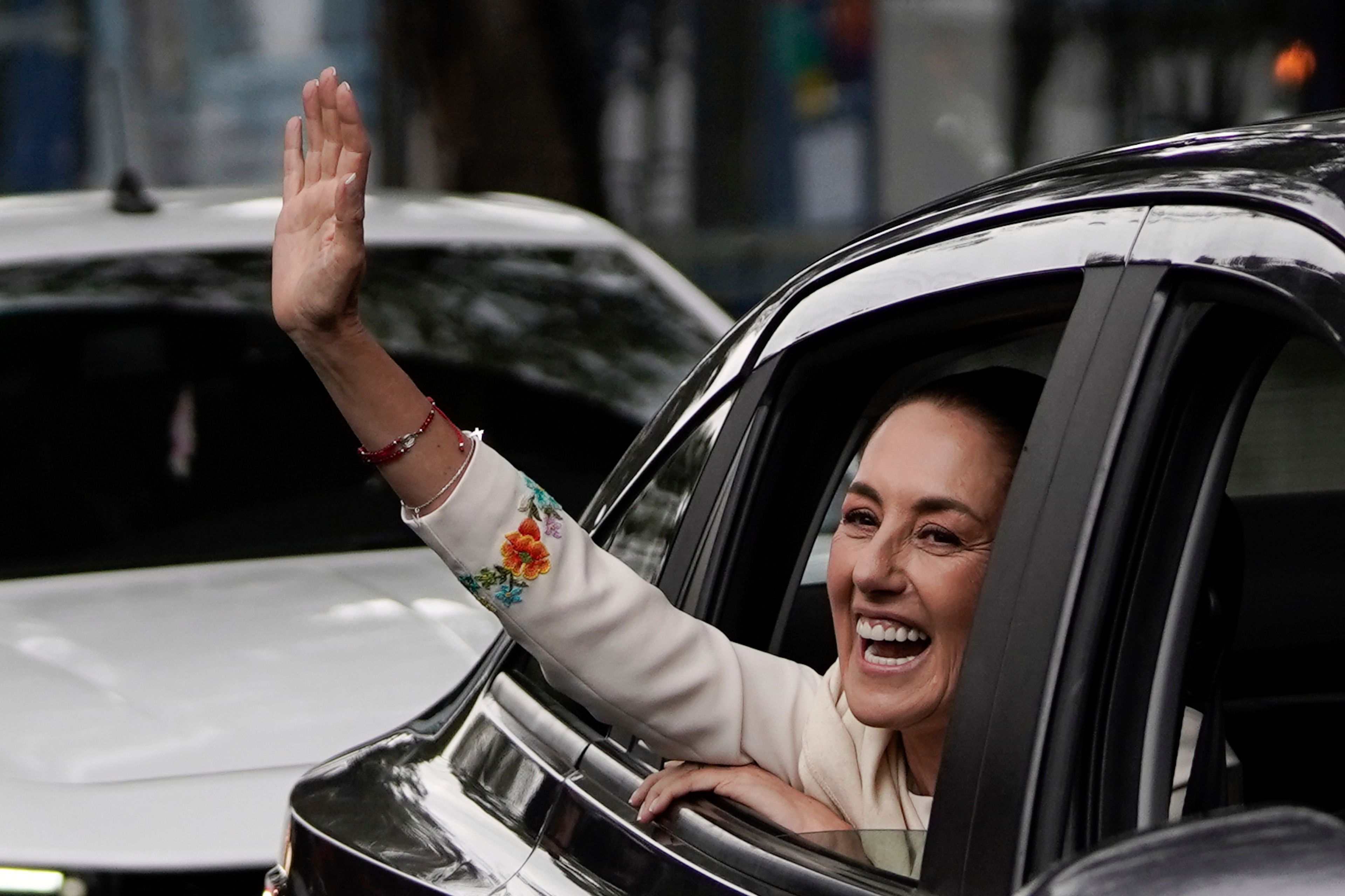 Claudia Sheinbaum waves from the vehicle taking her to Congress where she will be sworn in as president in Mexico City, Tuesday, Oct. 1, 2024. (AP Photo/Aurea Del Rosario)