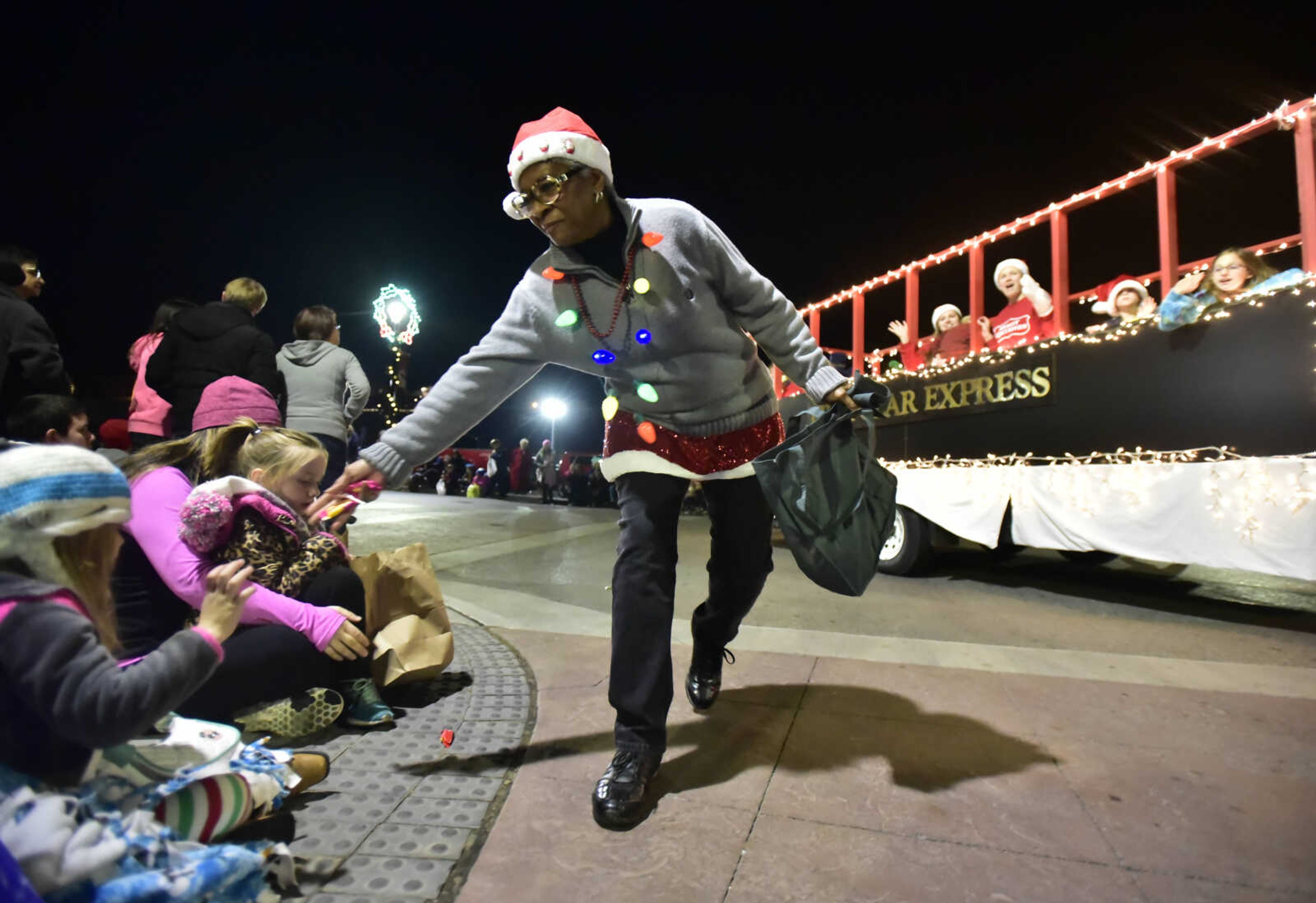 Fay Powders hands candy to children while walking alongside a float sponsored by Realty Executives in the 26th annual Parade of Lights Nov. 26, 2017, in Cape Girardeau.