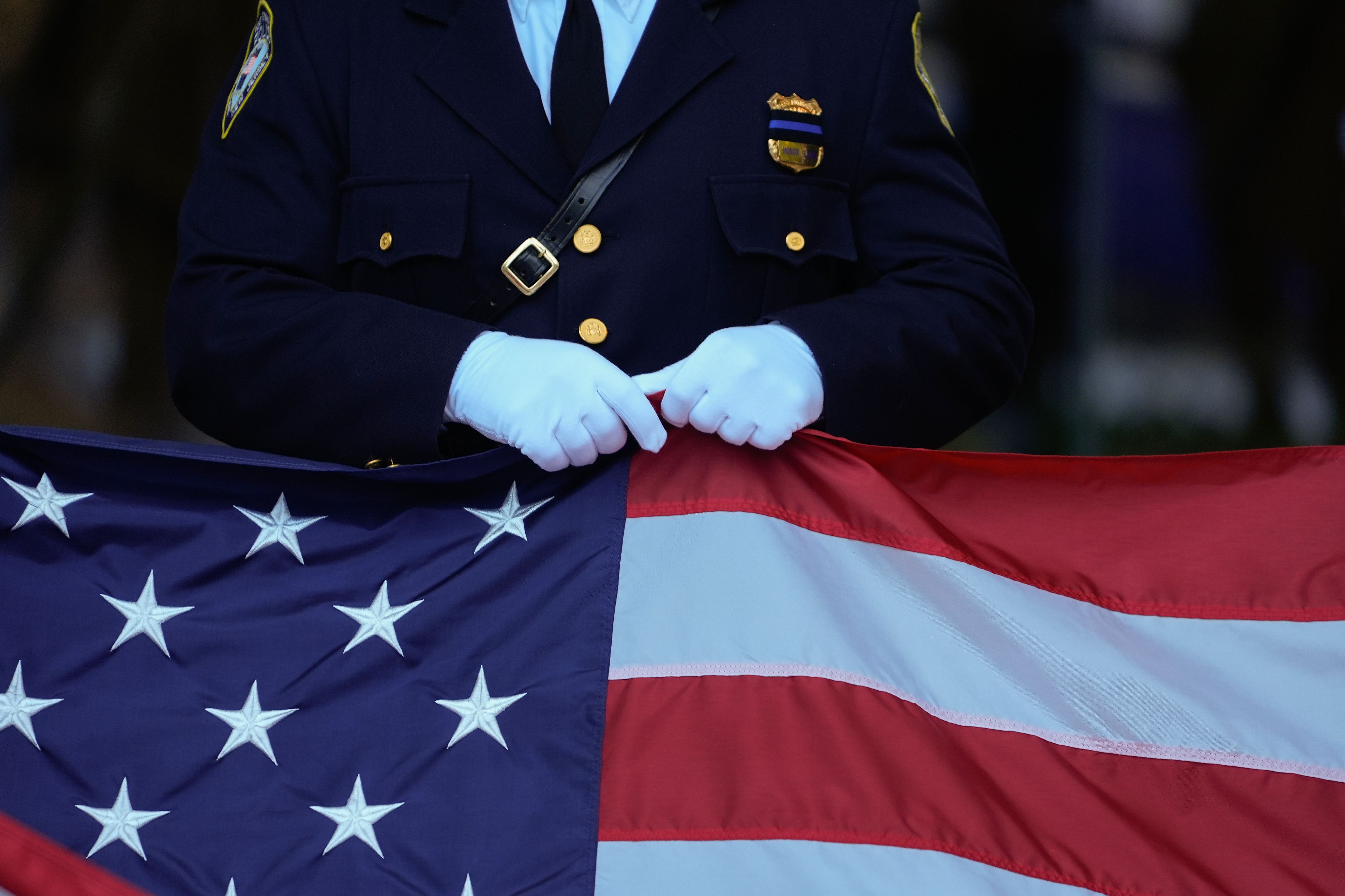 A New Jersey police officer holds an American Flag before the start of the ceremony at the 9/11 Memorial on the 23rd anniversary of the Sept. 11, 2001 attacks, Wednesday, Sept. 11, 2024, in New York. (AP Photo/Pamela Smith)